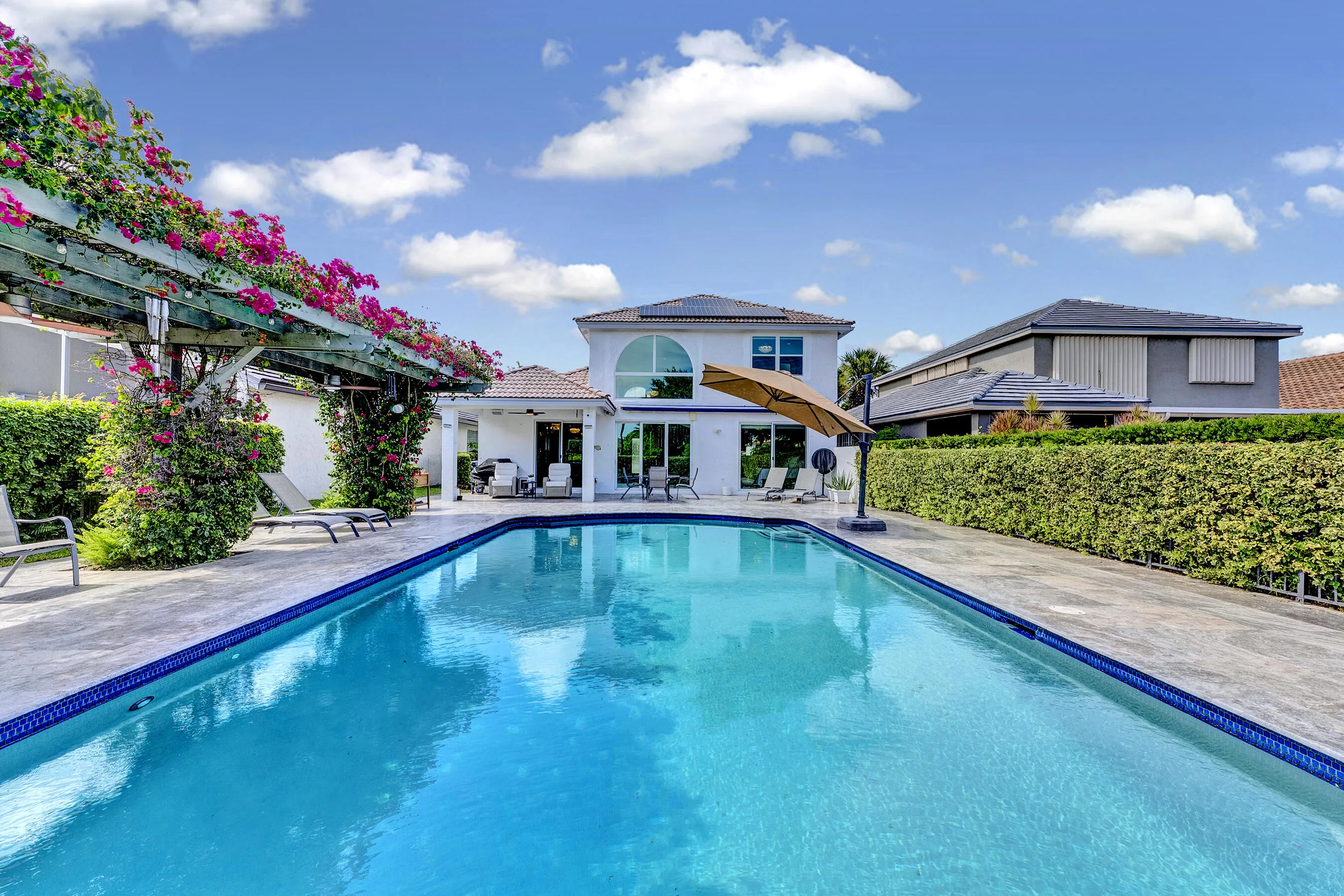 Long view across the oversized private pool toward the home's arched two-story rear elevation.