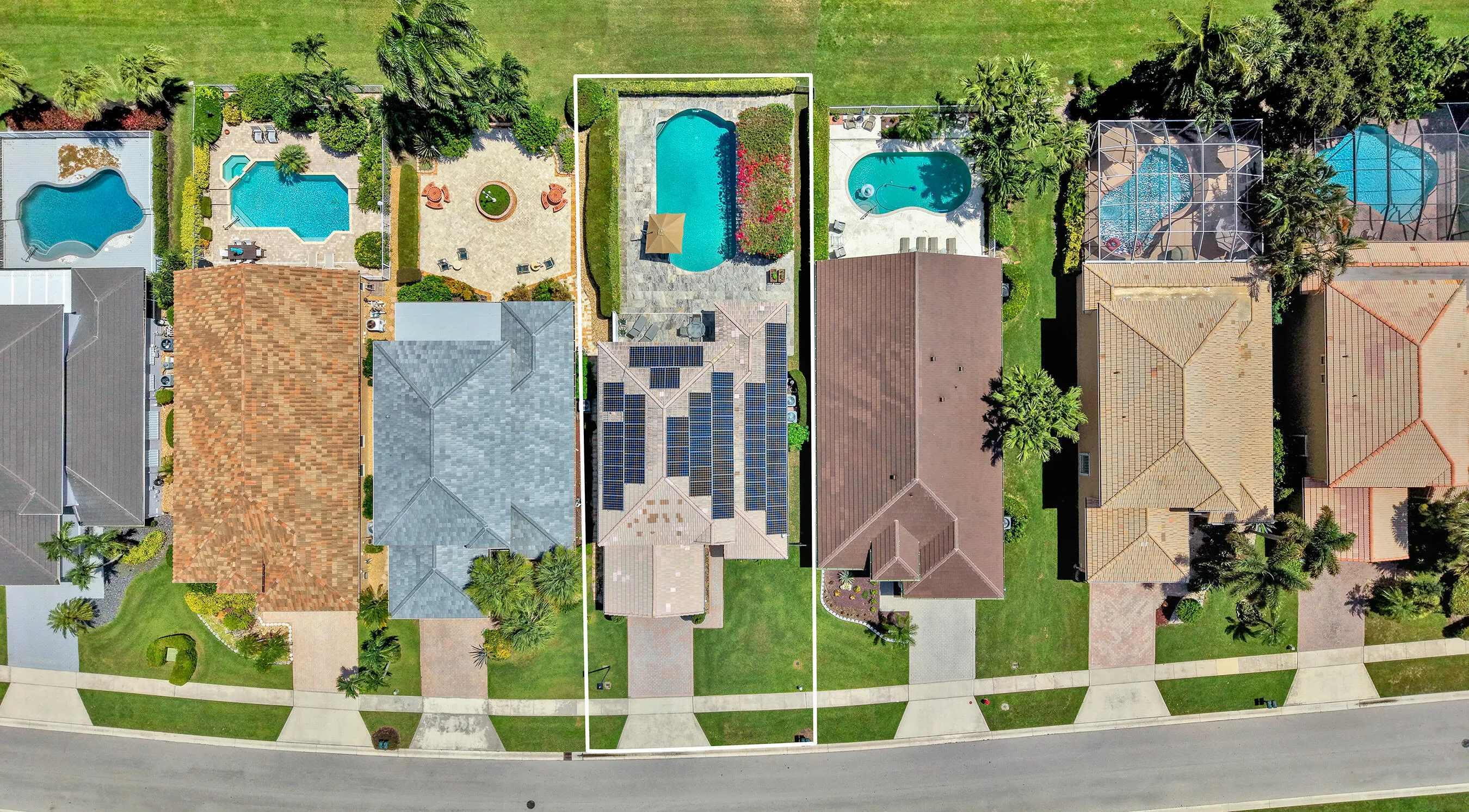 Top-down aerial of the full parcel showing pool, patio, paver drive, and lot boundaries.