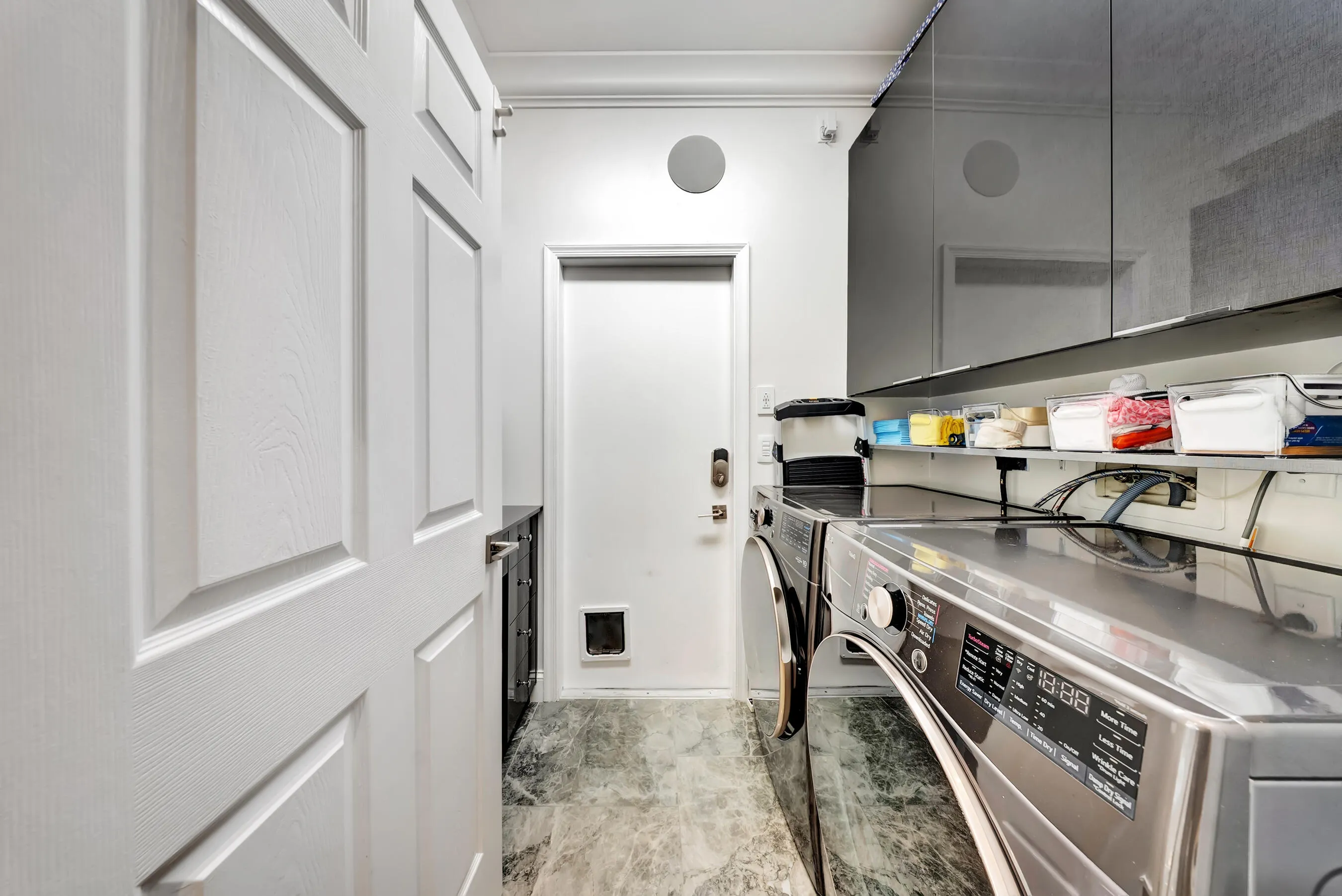 Dedicated laundry room with premium front-load washer and dryer and glossy storage cabinetry.
