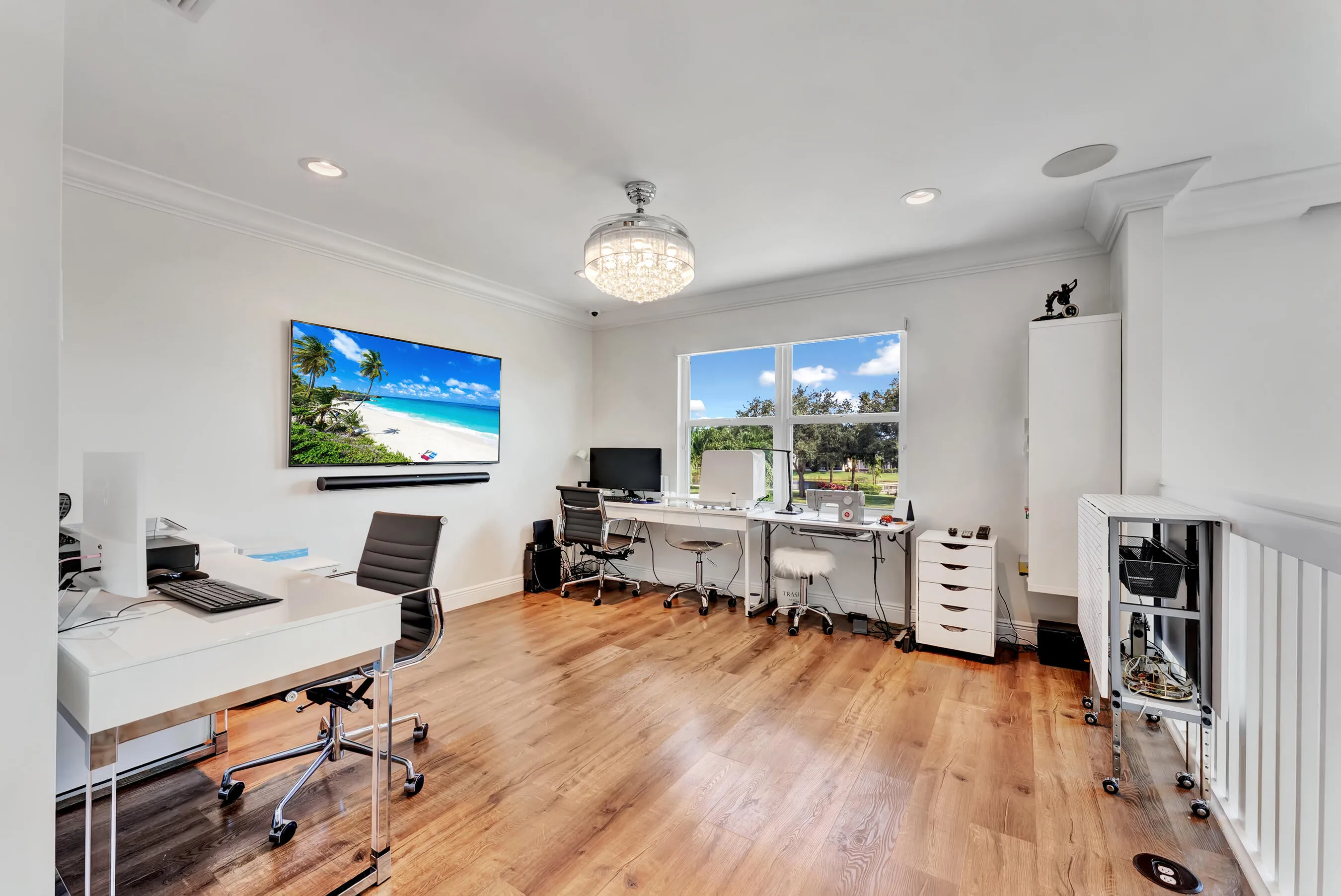 Versatile loft office with wood flooring, dual workstations, and treetop views; ideal work-from-home space.