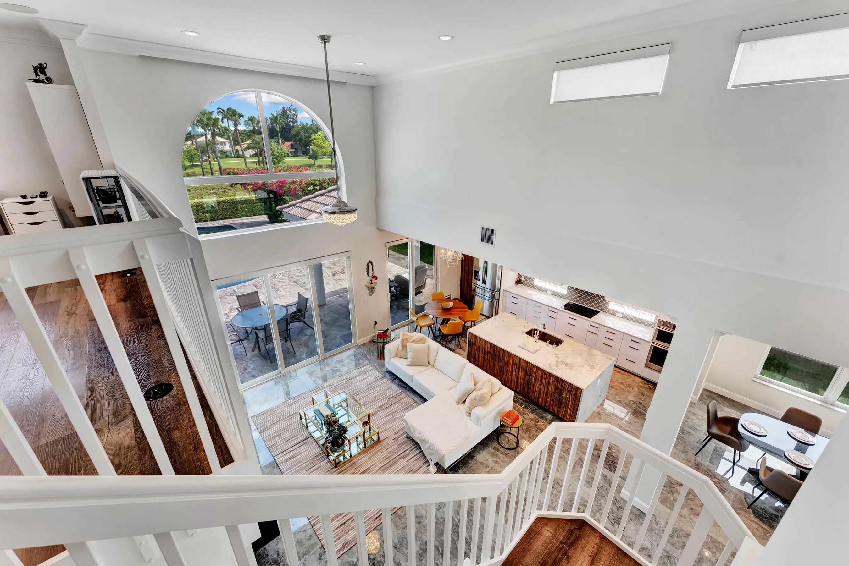 Upstairs loft overlooking the great room, kitchen, and pool through two-story windows.