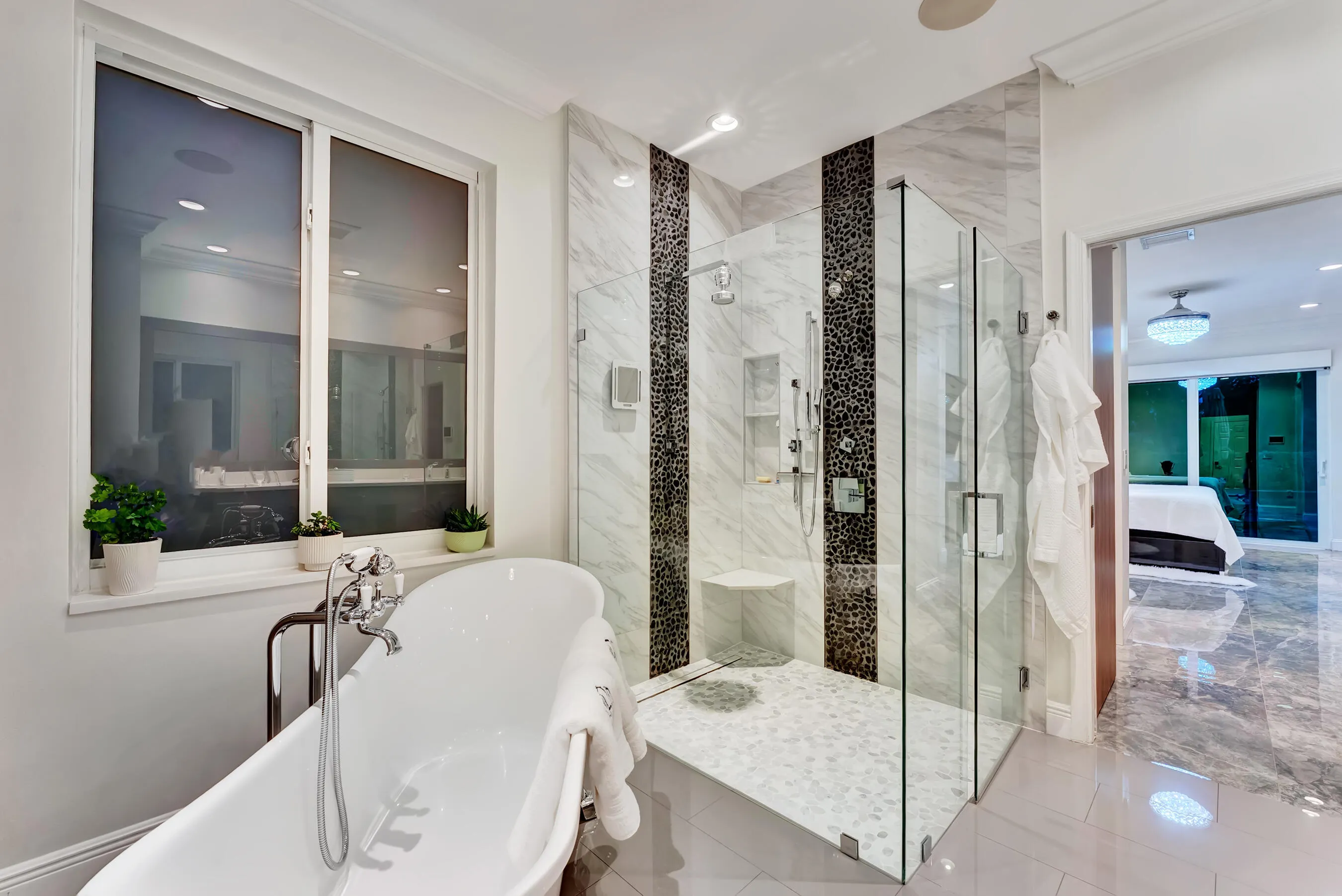 Primary bath at evening with soaking tub, glass shower, and view into the suite.