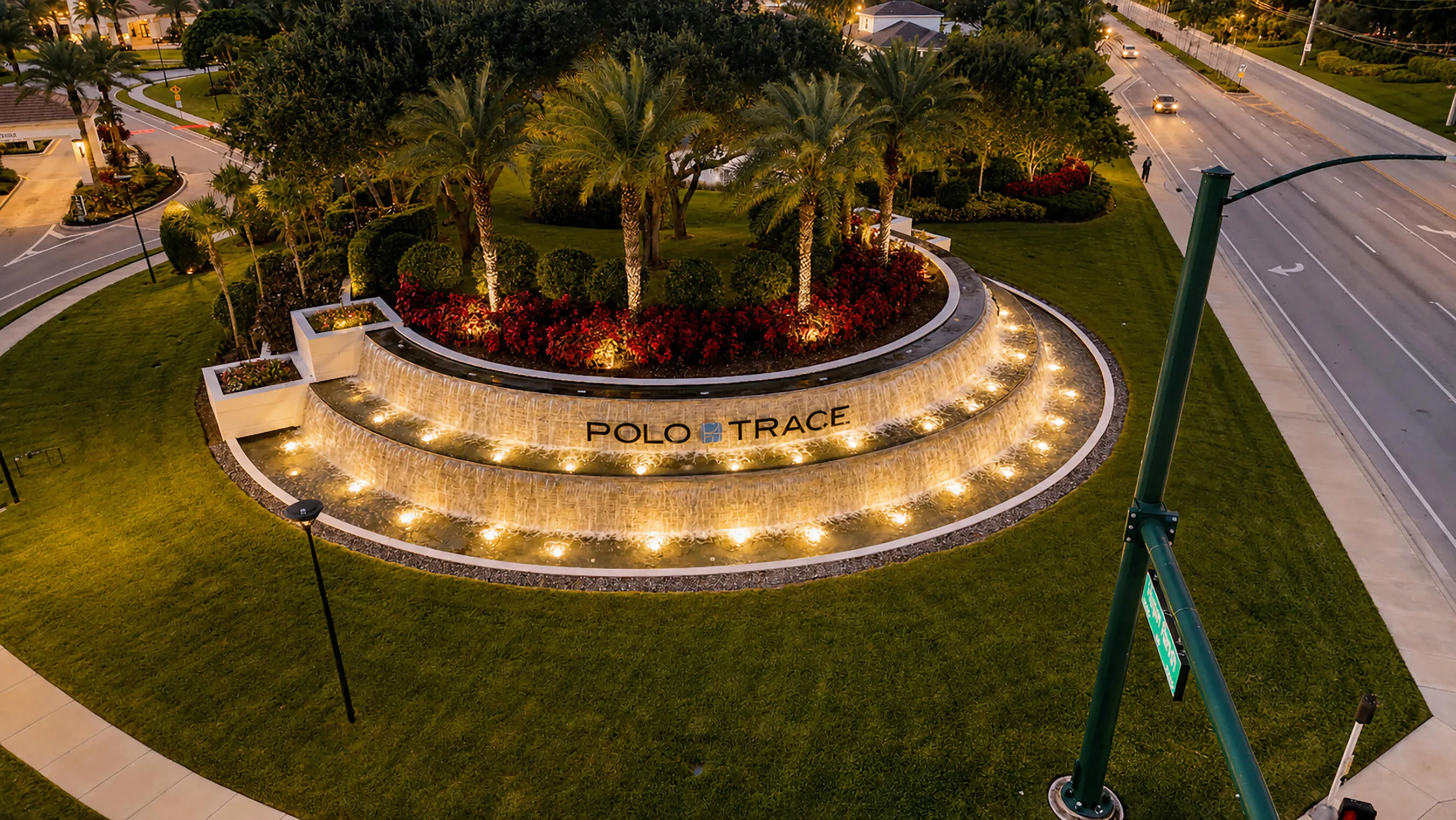 Close-up of the lit Polo Trace waterfall entry monument at dusk in Delray Beach, Florida.