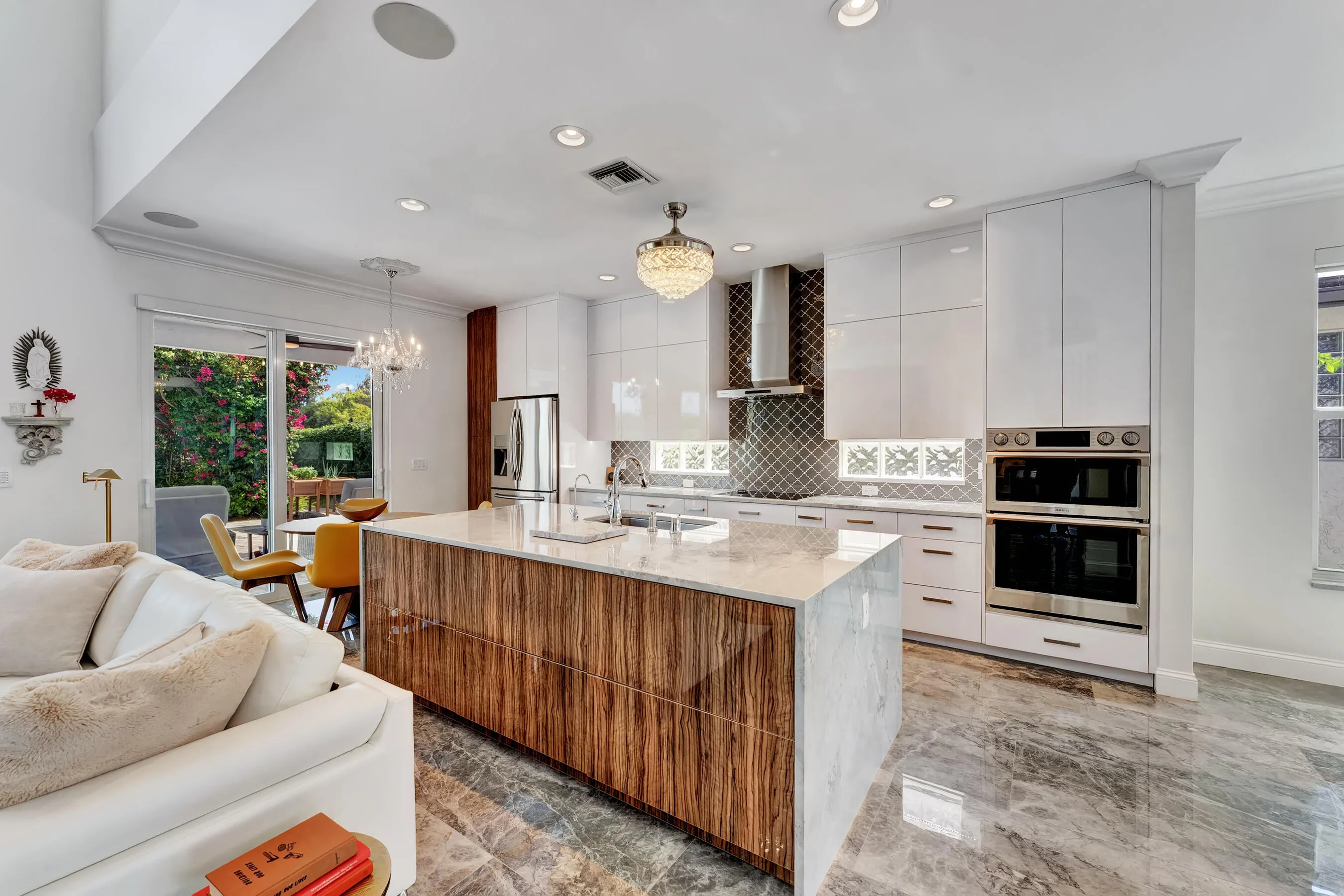 Fully renovated chef's kitchen with waterfall-edge quartzite island, exotic wood cabinetry, and high-gloss white uppers.