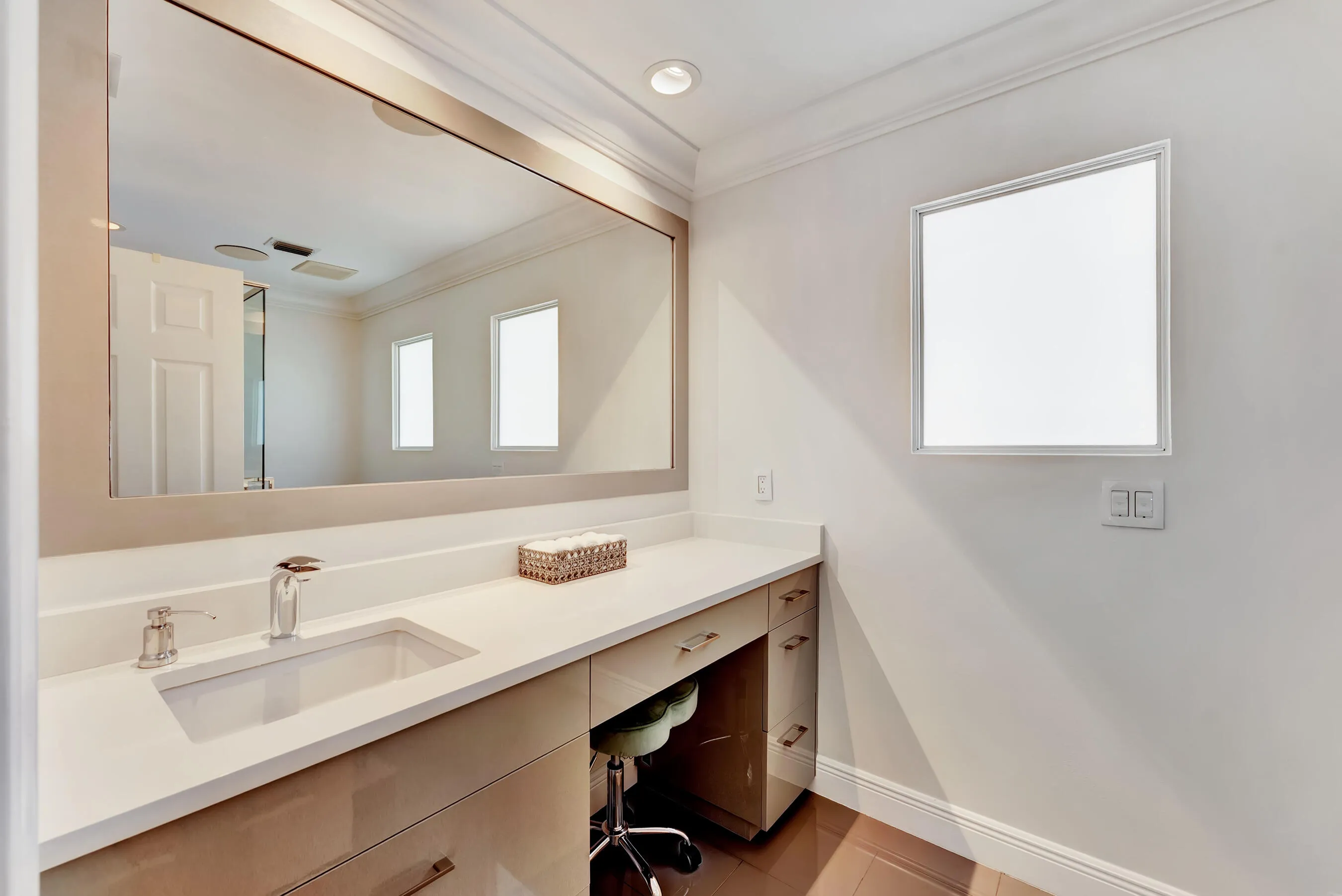 Upstairs bathroom with extended quartz-top vanity, seated station, and oversized mirror.