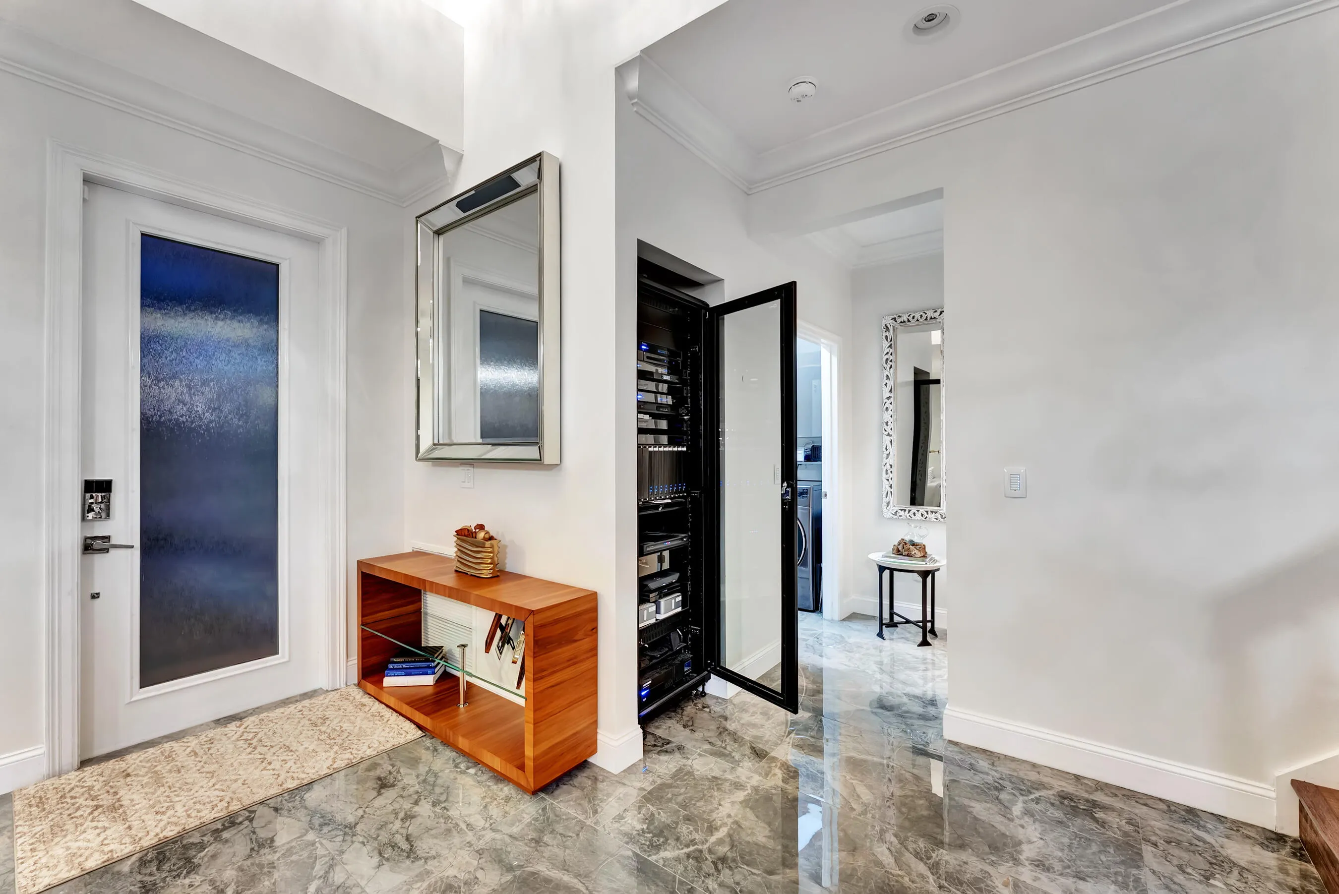 Foyer at dusk with glass front door, marble-look floors, and designer console.