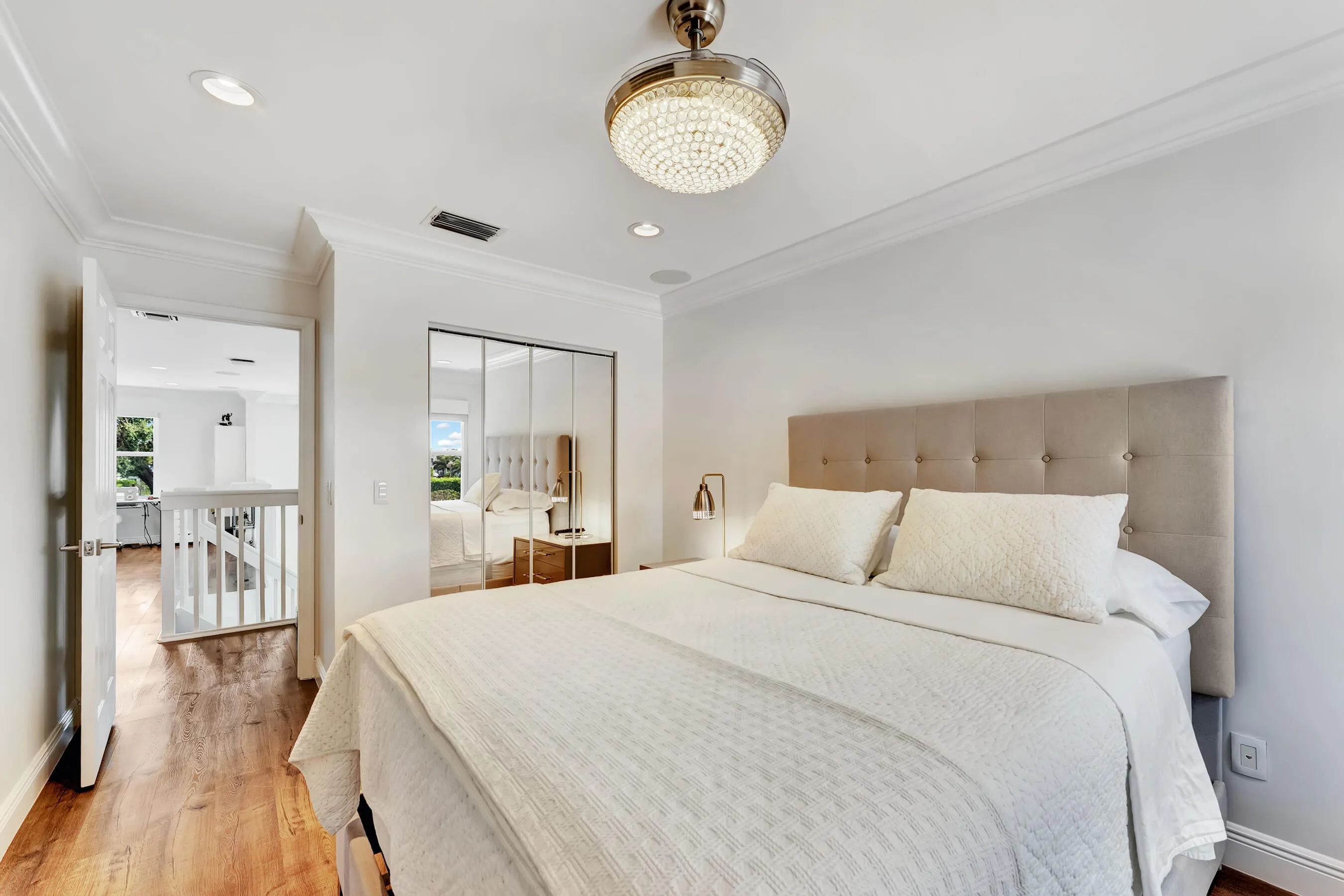 Guest bedroom with upholstered bed, garden views, and designer ceiling fixture.