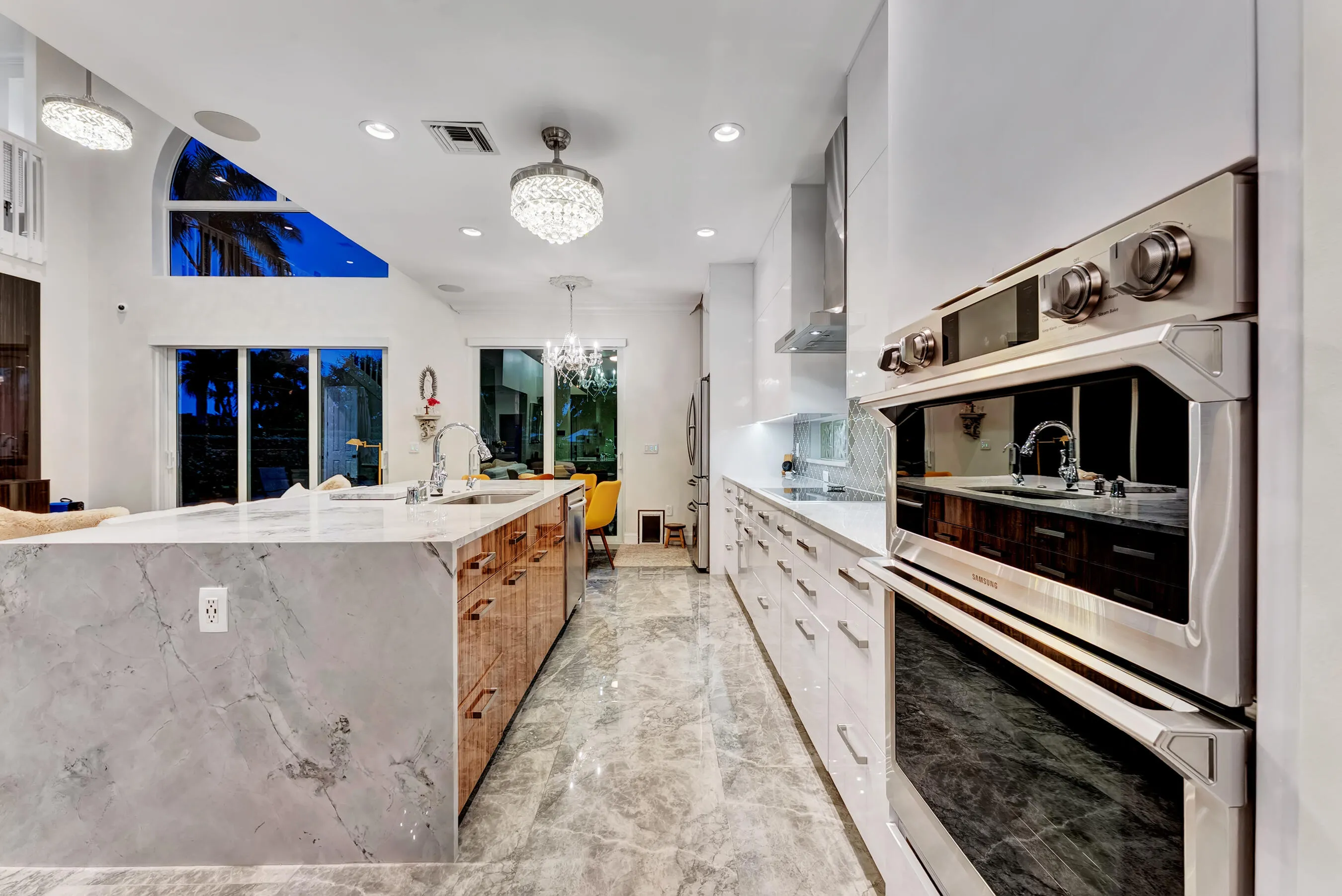 Chef's kitchen at dusk highlighting the waterfall island and under-lit designer finishes.