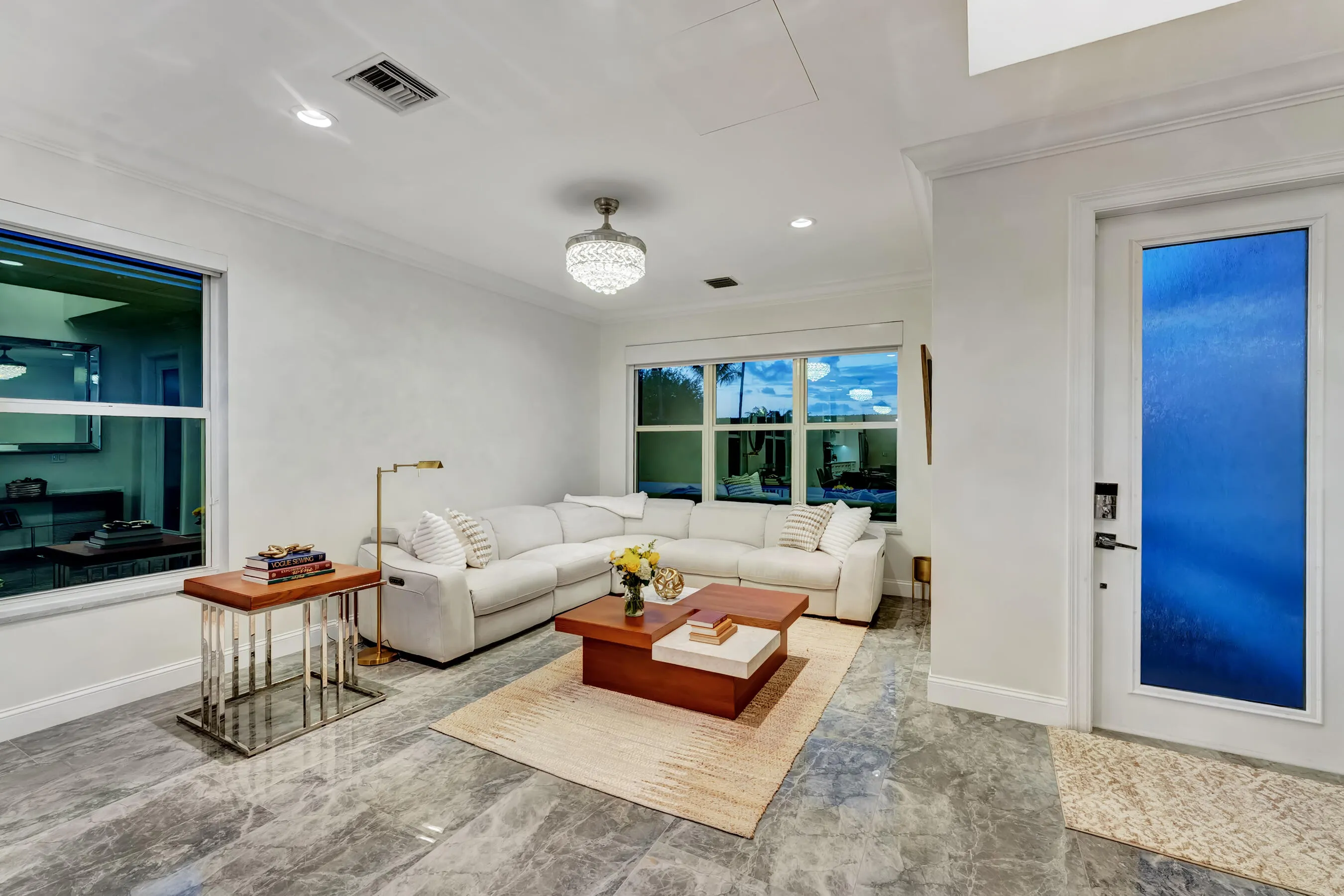 Living room at dusk with soft designer lighting and views to the illuminated front landscape.