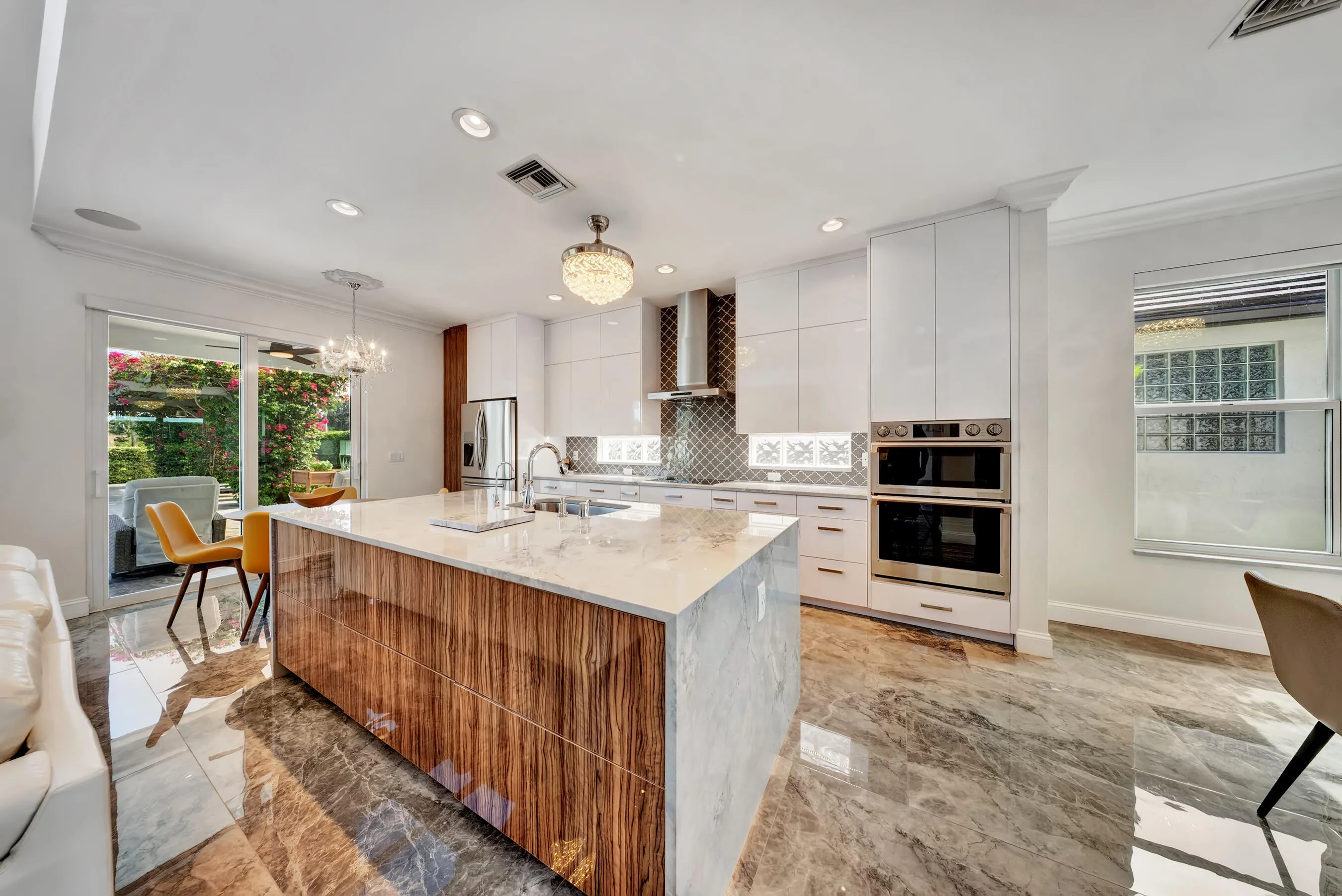 Kitchen island with views through sliding doors to the covered patio and tropical backyard.