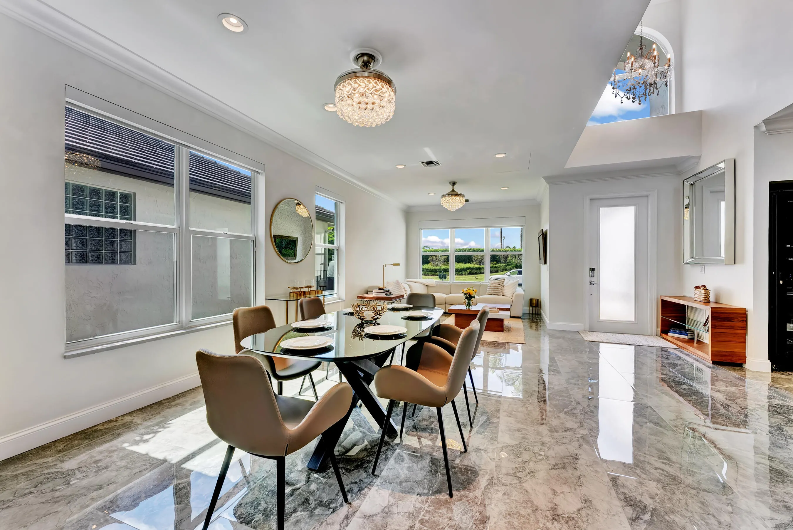 Dining area with contemporary table seating, dual accent mirrors, and natural light from front-facing windows.