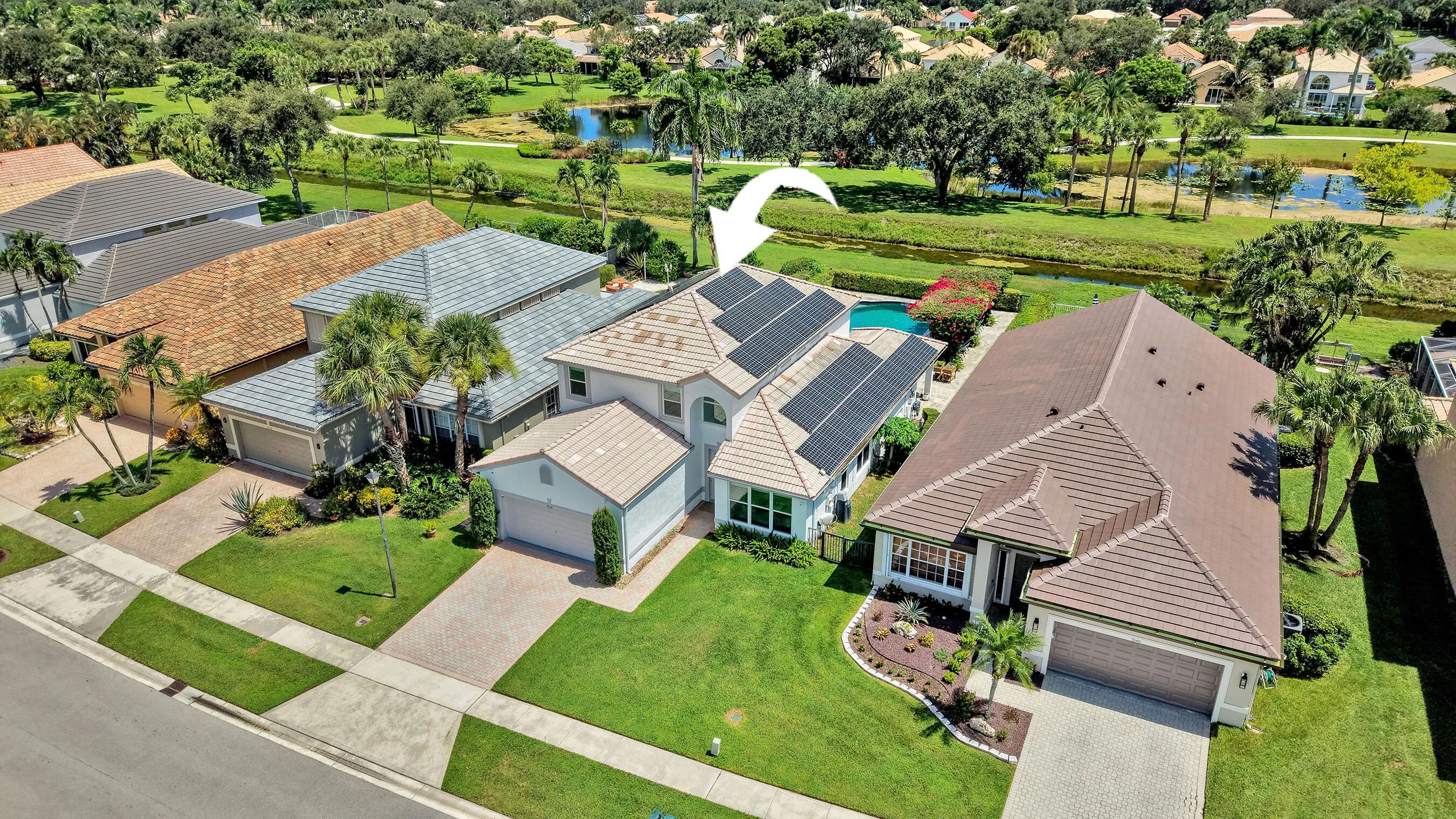 Angled aerial showing the tile roof, solar panel array, pool, and landscaped lot.
