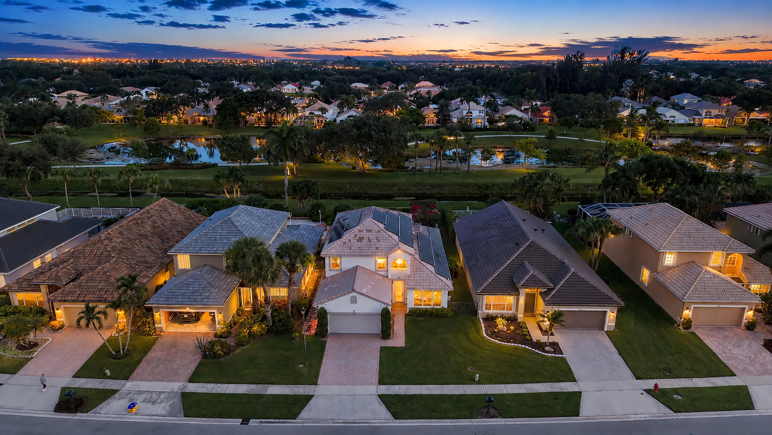Twilight aerial above the street showing the home among the lakefront residences of Polo Trace, Delray Beach.