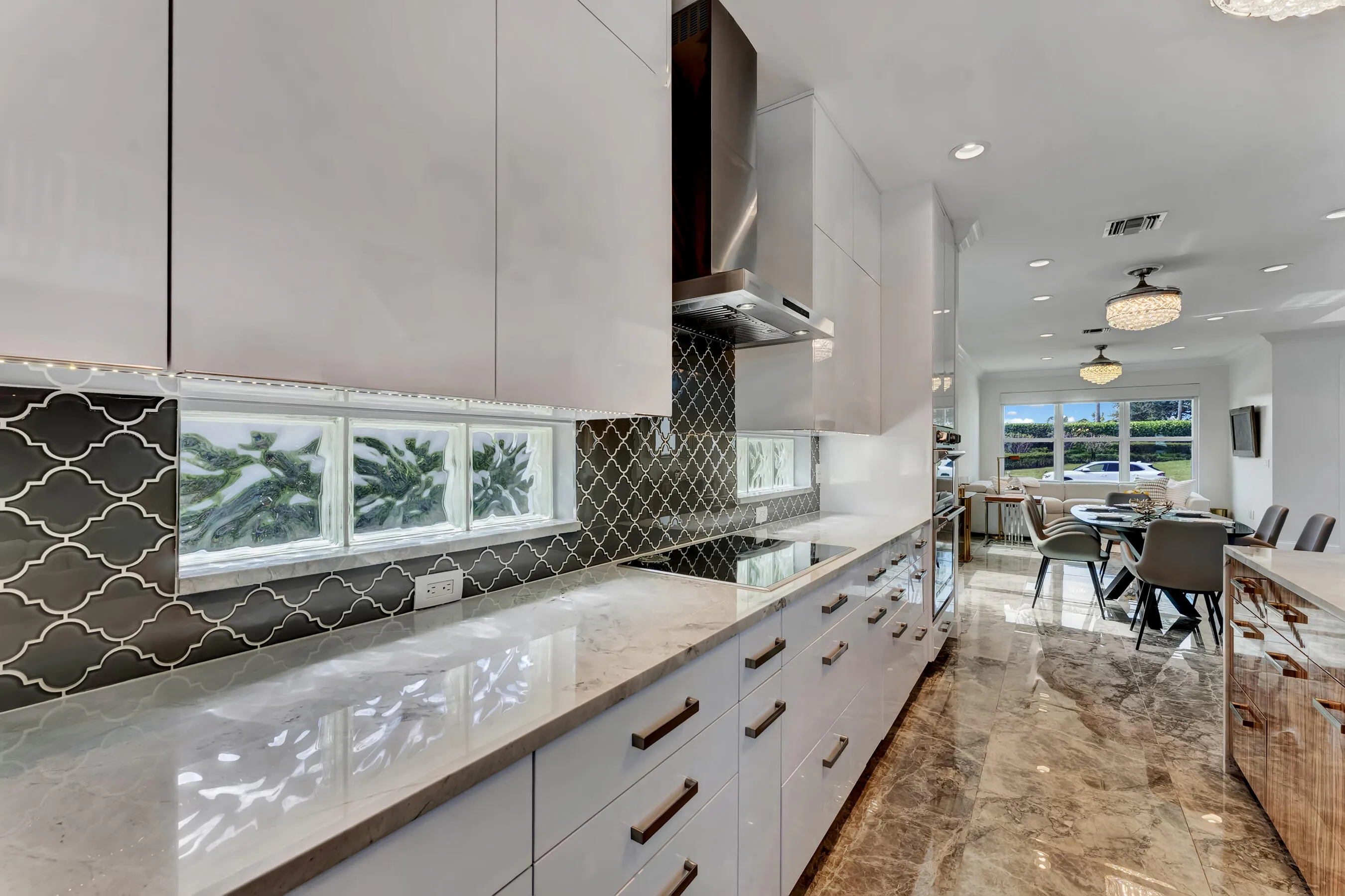 Kitchen counter run with glass-block accent windows, induction cooktop, and modern European-style cabinetry.