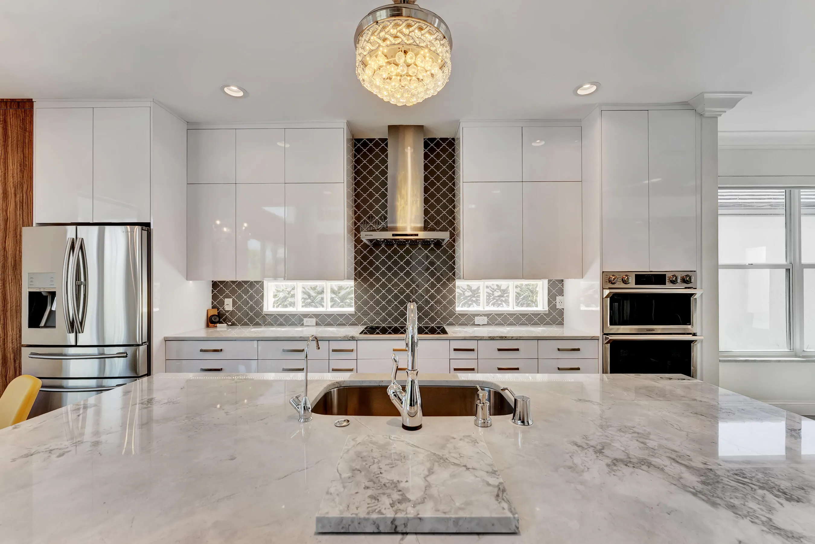 Kitchen work zone with built-in stainless wall ovens, sleek hardware, and expansive stone countertops.