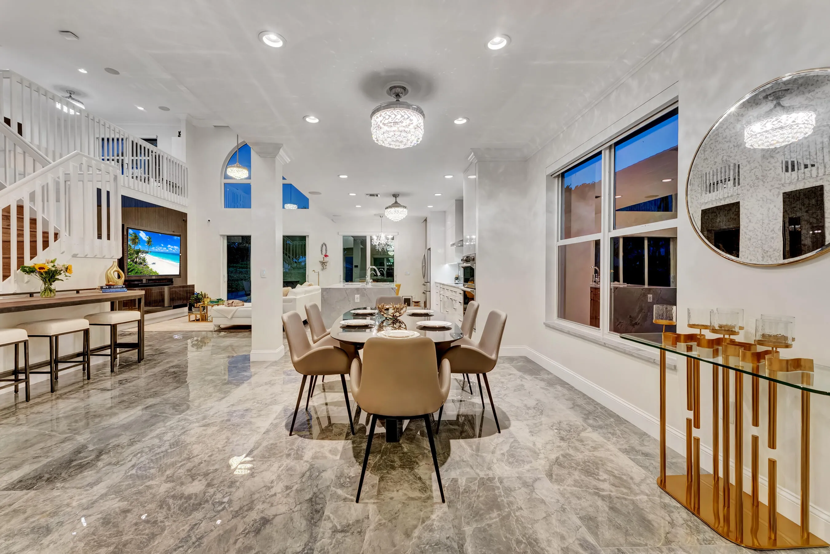 Open dining and kitchen at evening with chandeliers and crystal fixtures aglow.