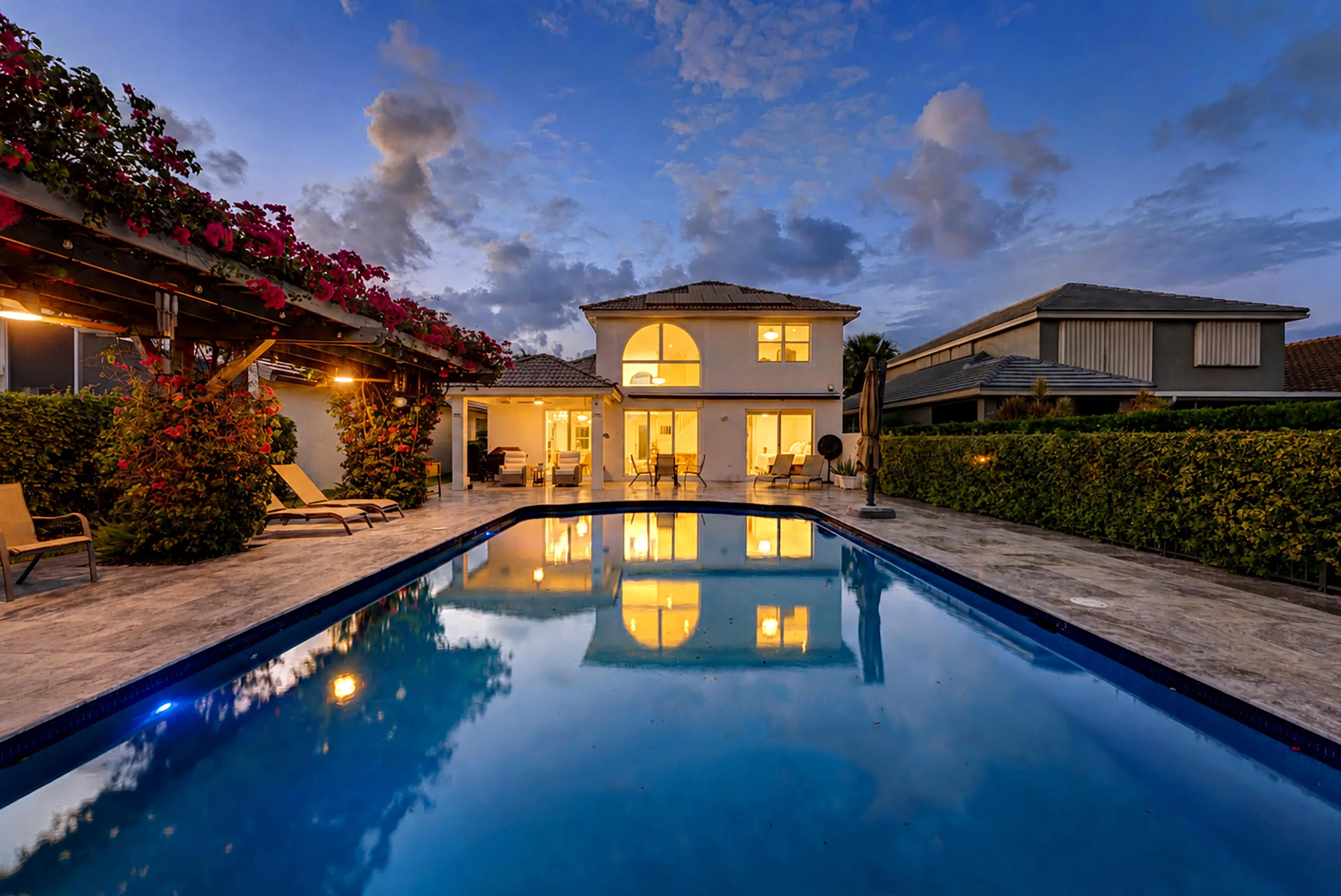 Evening pool view with mirror-like reflections of the home's lit rear elevation.