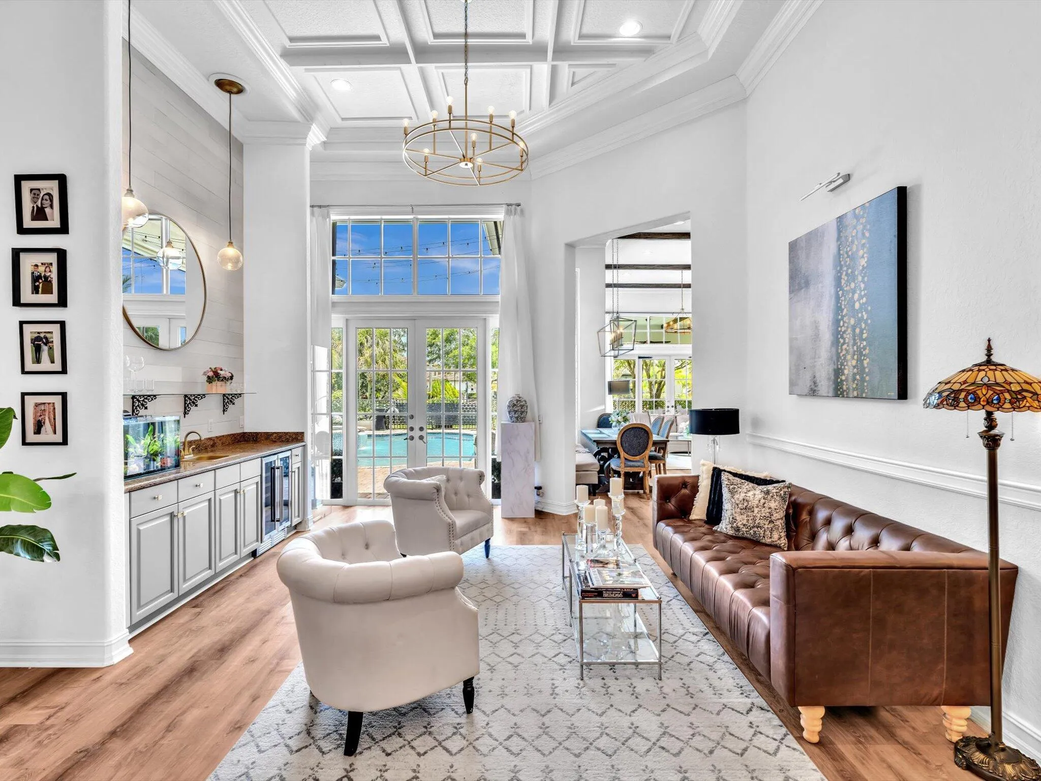 FORMAL LIVING ROOM WITH COFFERED CEILINGS, A WET BAR, WAINSCOTTING, WINE FRIDGE, SPECIALTY WINE DISPLAY AND SLIDING DOORS TO OUTSIDE AREA.