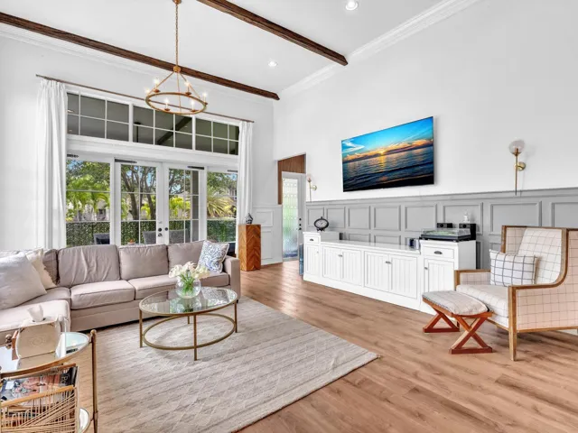 THIS OVERSIZED FAMILY ROOM WITH BEAM CEILINGS WAINSCOTTING AND GLASS DOORS LEADING TO COVERED PATIO