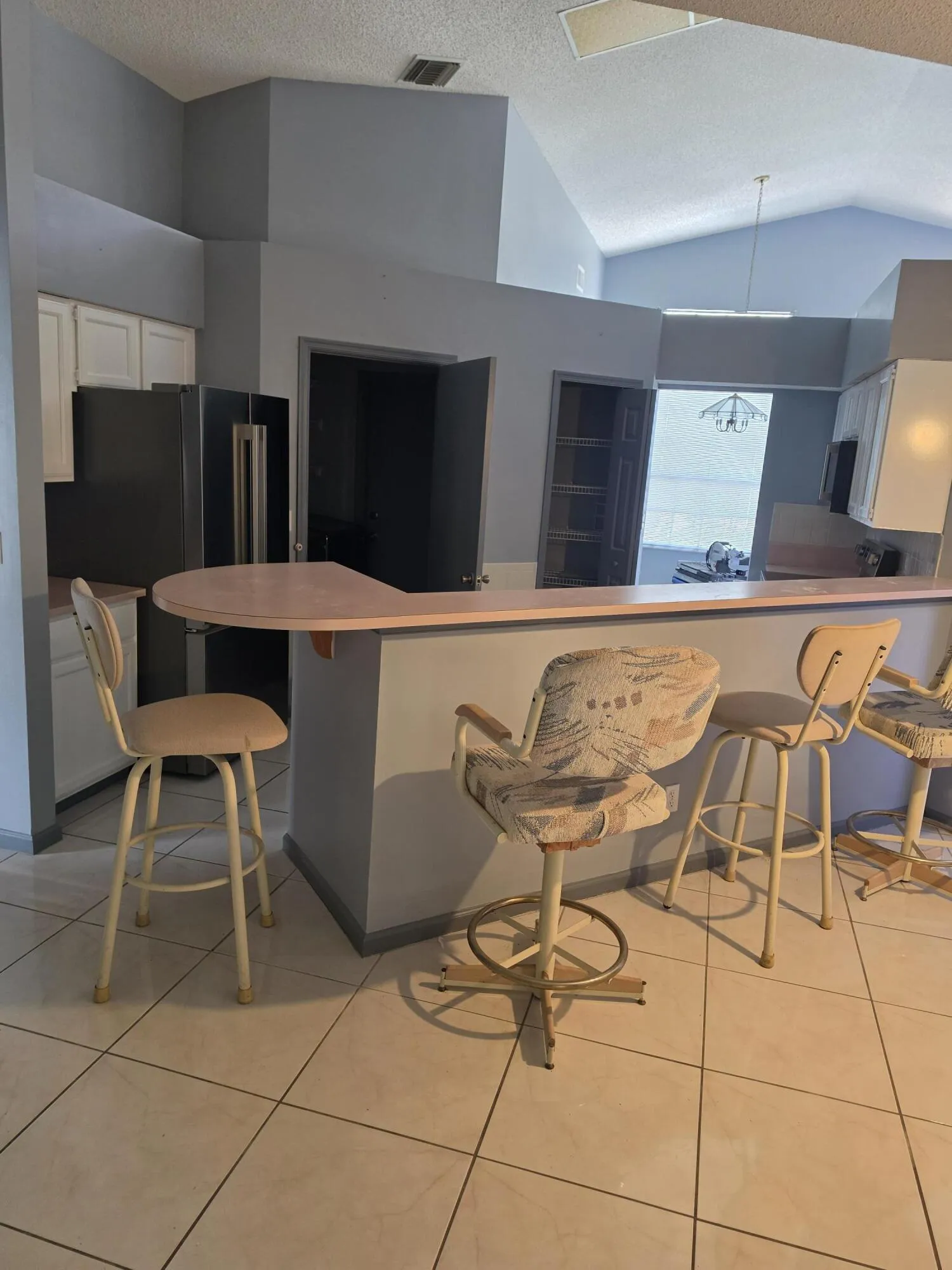 Kitchen featuring a breakfast bar with an extended counter, tile flooring, recessed lighting, and white cabinetry