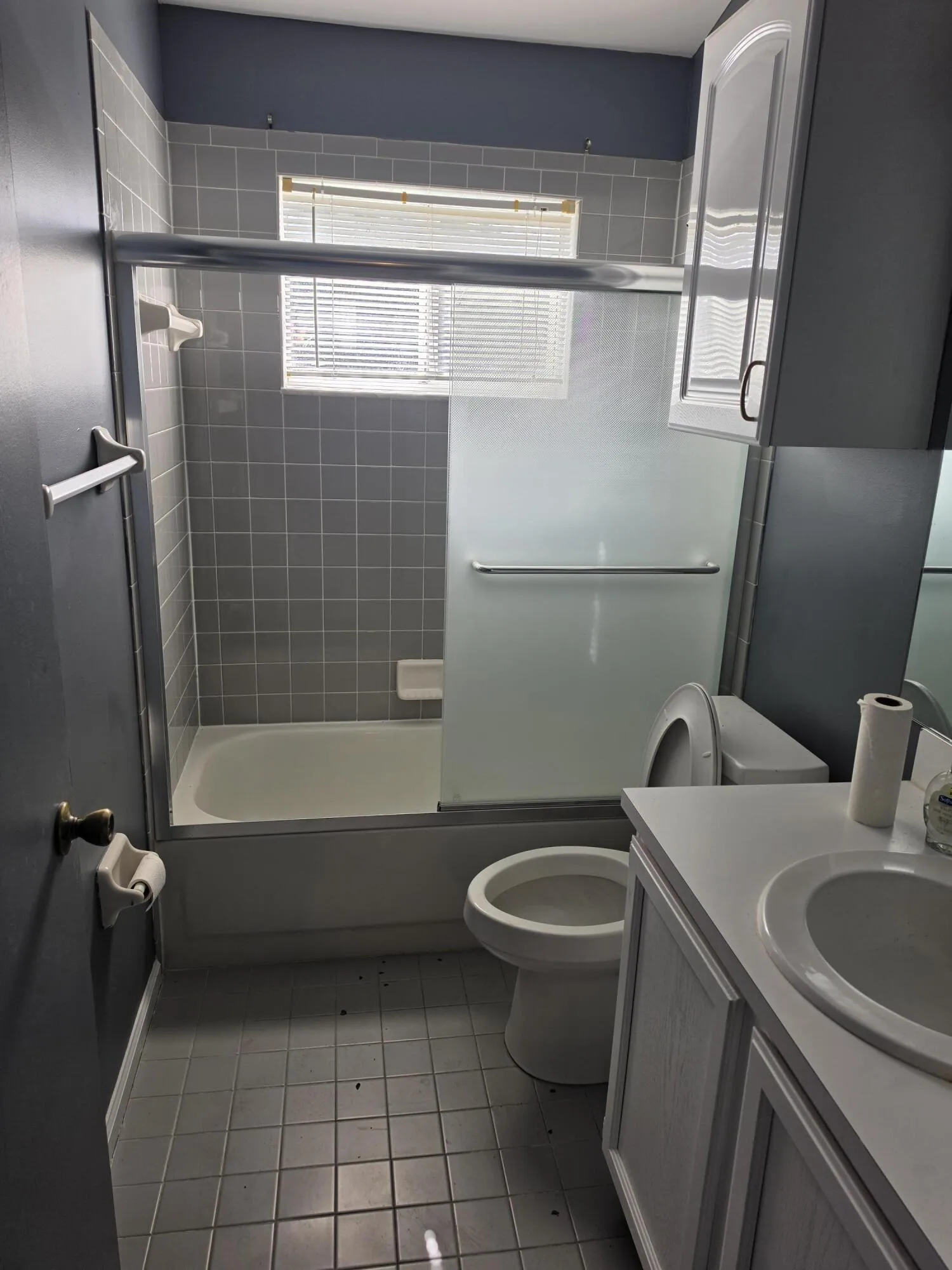 Bathroom featuring a tiled shower enclosure with a clear glass panel, a white vanity with an integrated sink, and a commode
