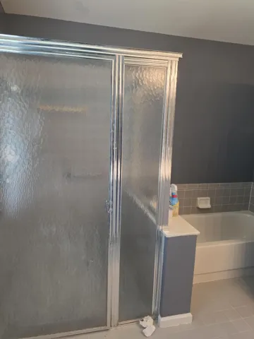 Tub/shower combination featuring a sliding glass enclosure with textured panels