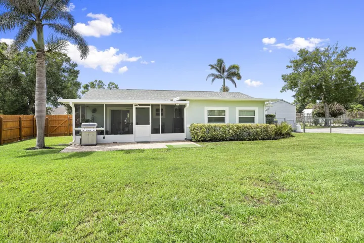 Expansive green lawn surrounds a single-story residence with a screened lanai and an extended patio