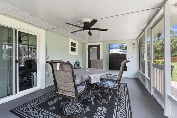 Screened-in back porch with ceiling fan and finished floor.
