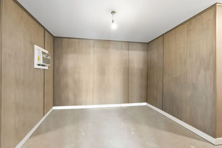Office area inside of the detached workshop. Panel walls and window AC unit.