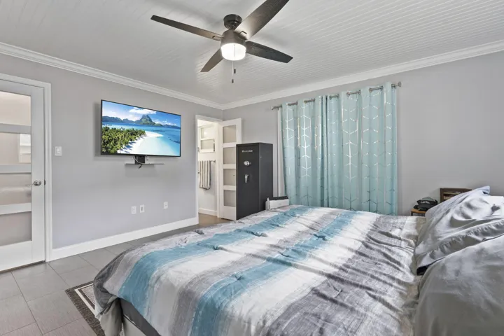 Beadboard ceiling with crown molding, ceiling fan, and gray tile flooring