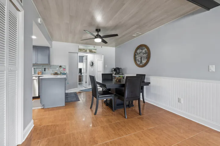 Dining area with wood-finish flooring, beadboard wainscoting, and a ceiling fan