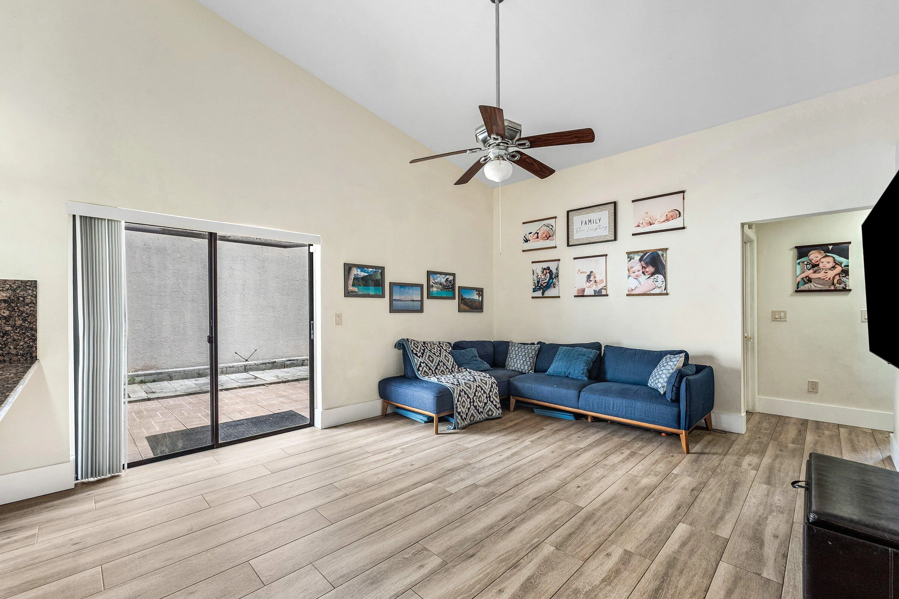 Vaulted ceiling living area featuring wood-finish flooring and a ceiling fan