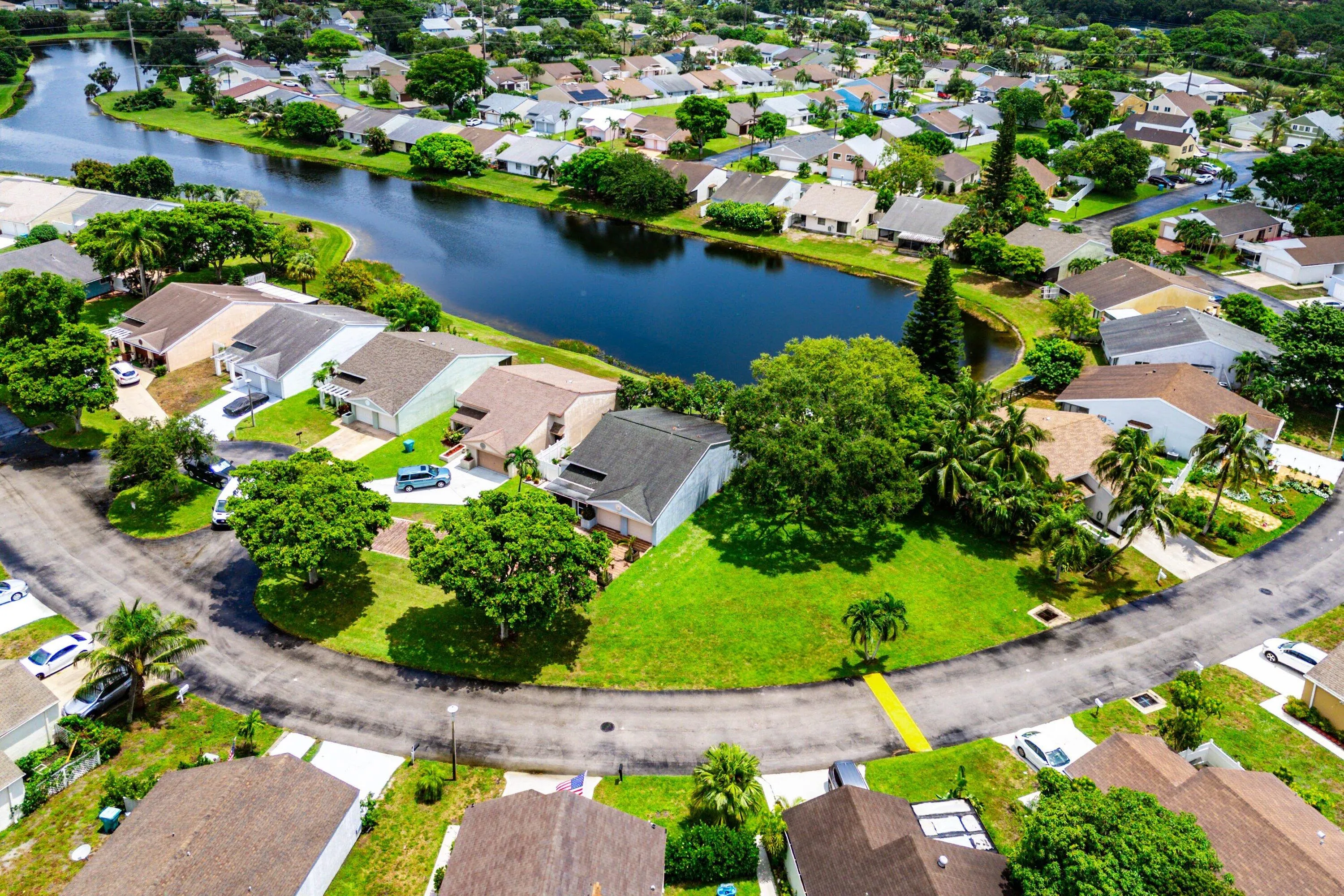 Residential neighborhood with a prominent body of water, featuring single-story homes, mature trees, and landscaped properties