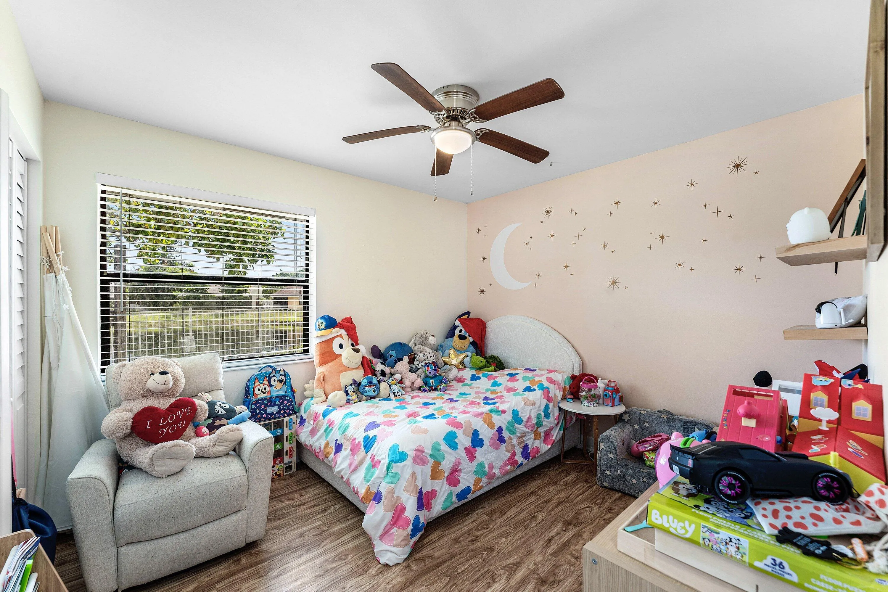 Bedroom featuring wood-finish flooring, a ceiling fan with light fixture, and a window with horizontal blinds