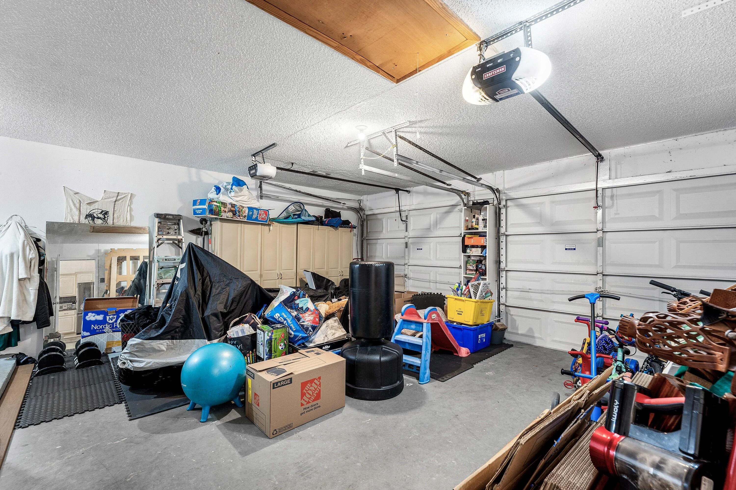 Spacious garage featuring two overhead garage doors, concrete flooring, overhead storage, and built-in cabinetry