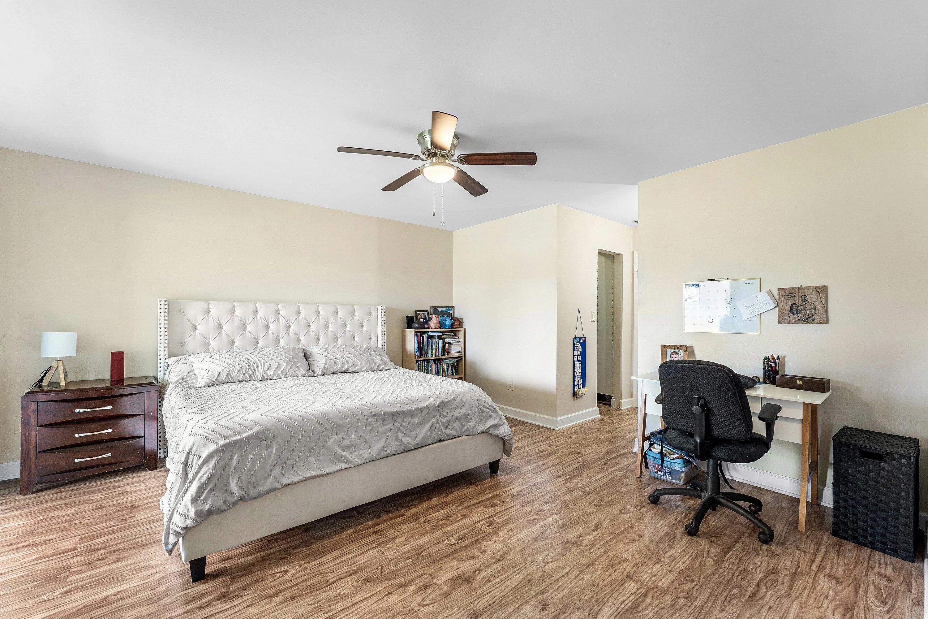 Spacious room featuring wood-finish flooring, light-toned walls, and a ceiling fan