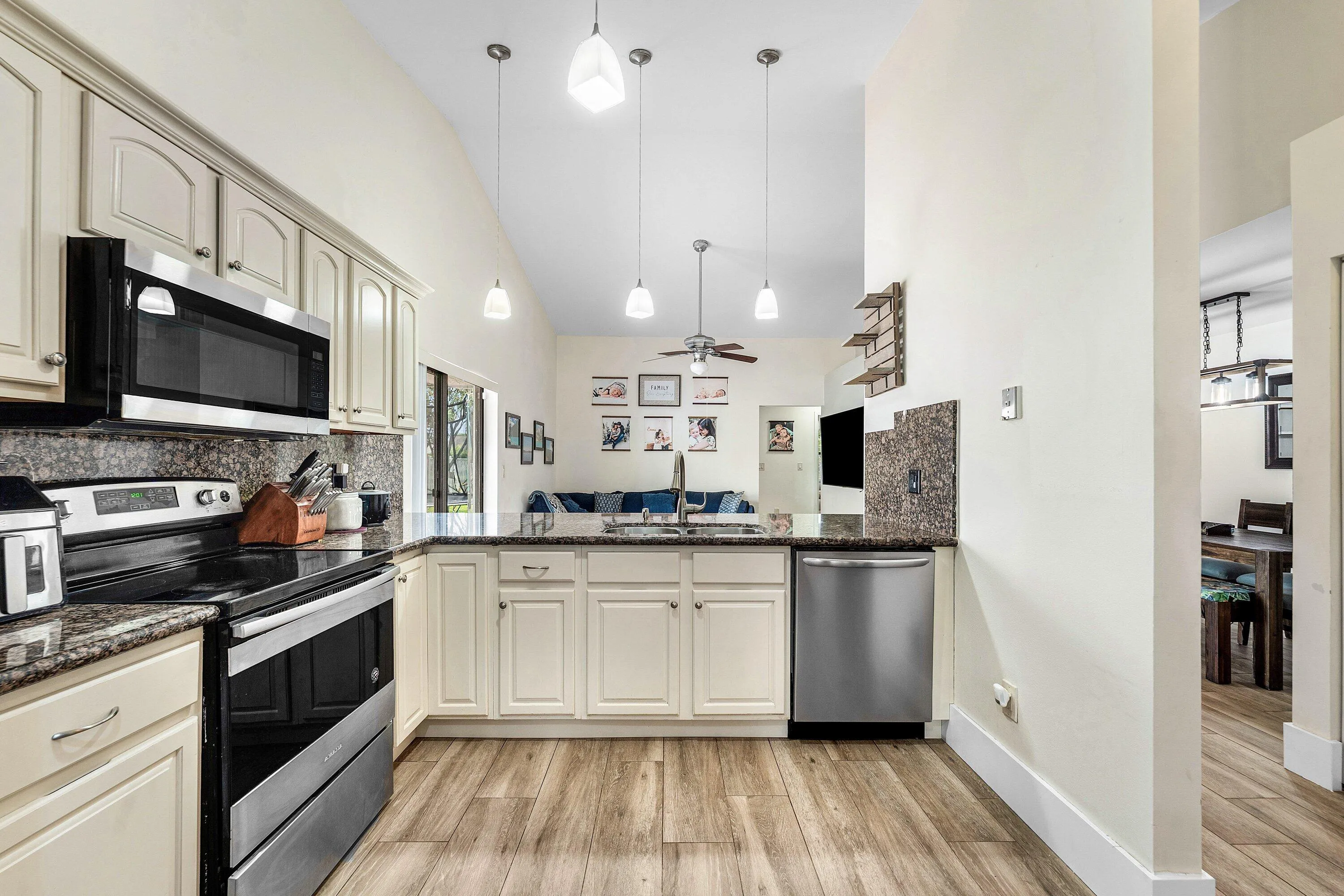 Kitchen featuring wood-finish flooring, cream cabinetry, dark stone countertops, and stainless steel appliances