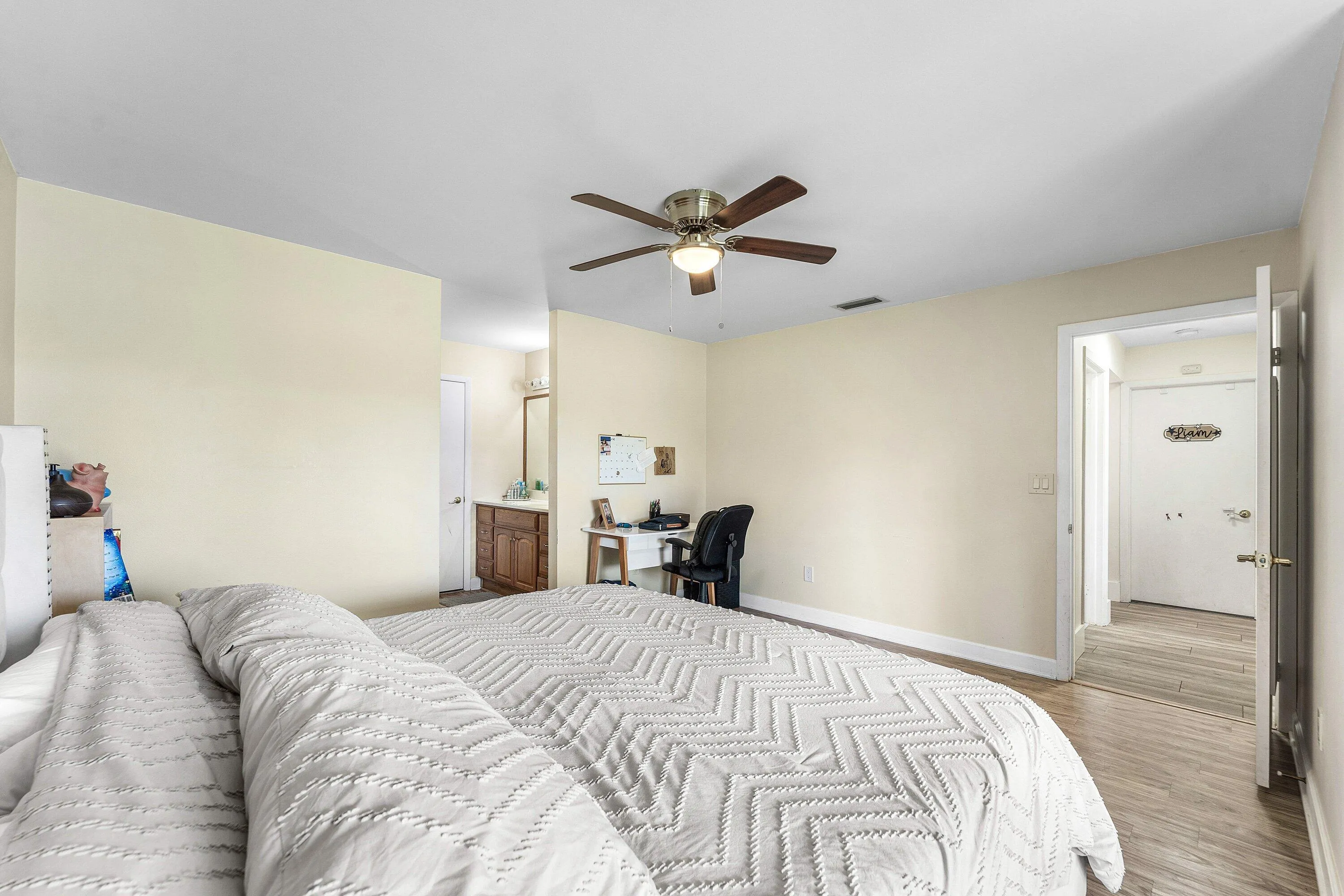 Spacious room featuring light-toned walls, wood-finish flooring, and a ceiling fan with integrated lighting