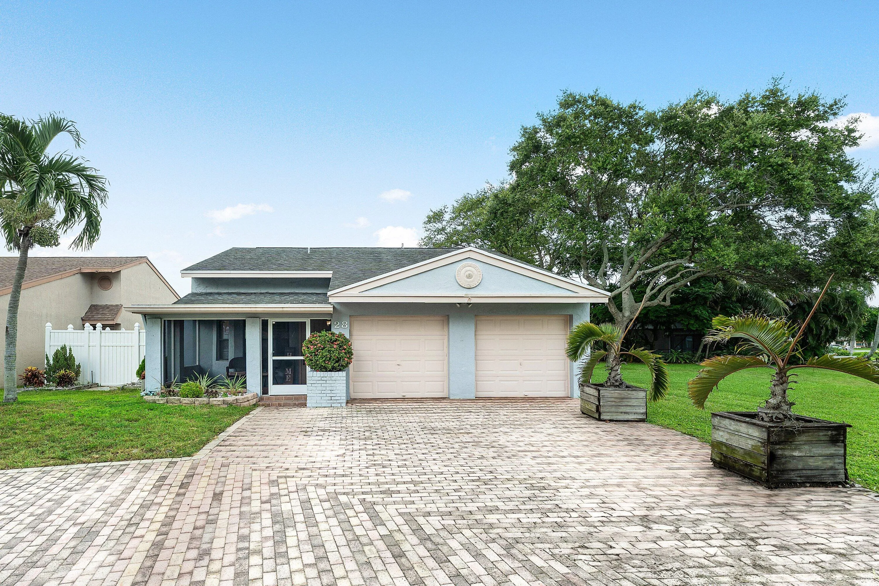 Light blue exterior with a two-car garage, screened-in porch, and a patterned paver driveway
