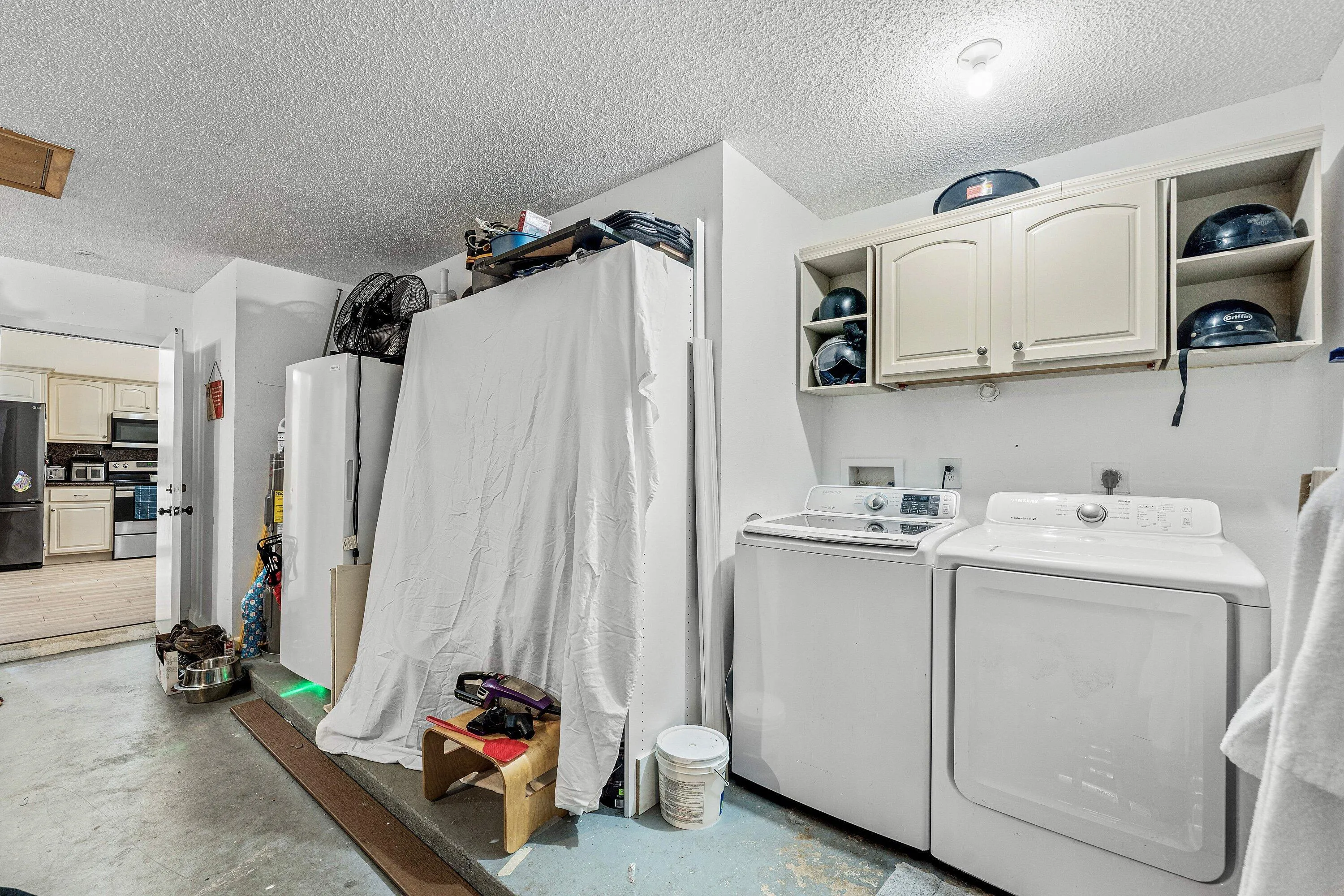 Dedicated laundry area featuring white upper cabinetry with open shelving and closed storage