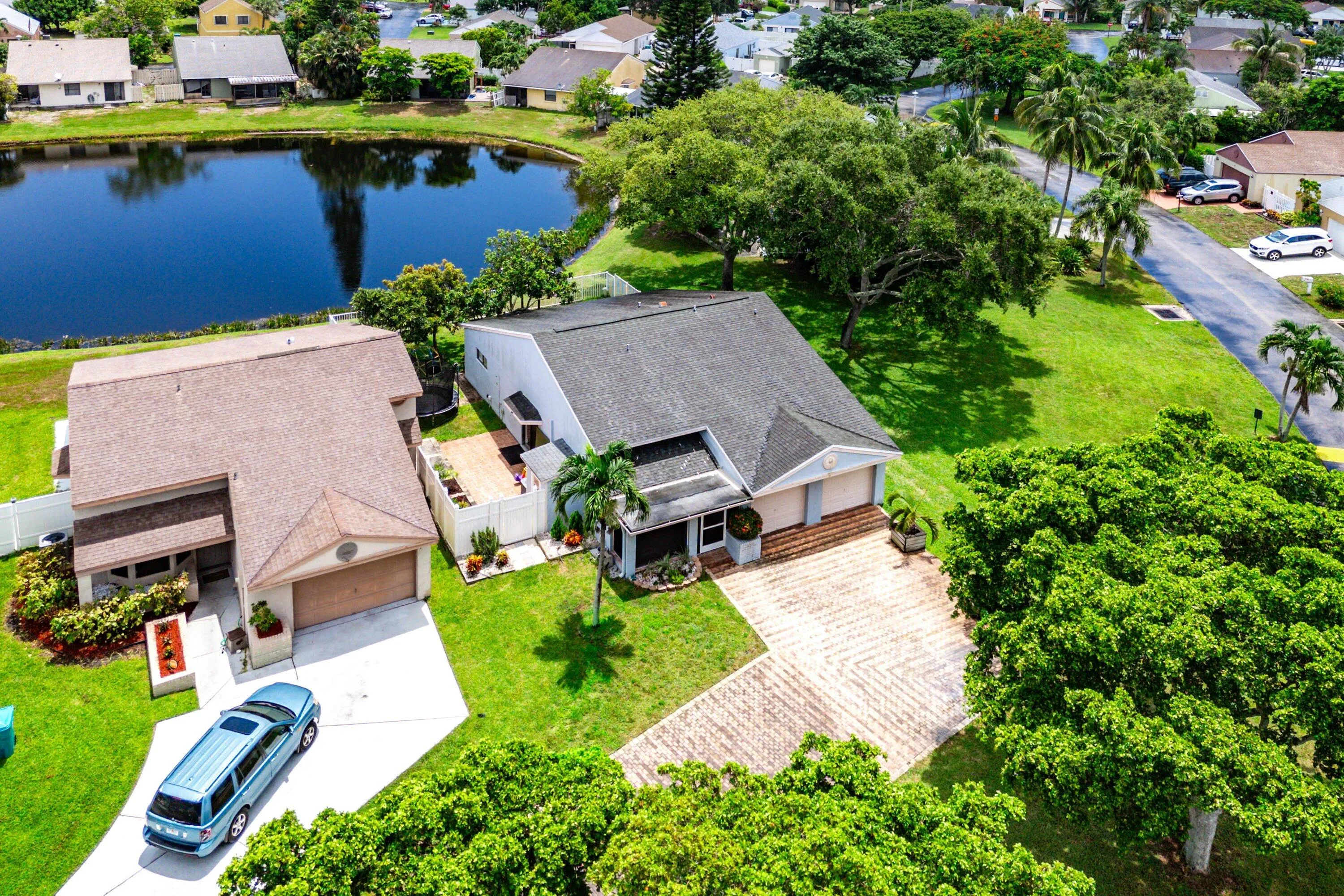 Single-family residence with a water feature backdrop, featuring a paver driveway, an attached two-car garage, and a lush green lawn