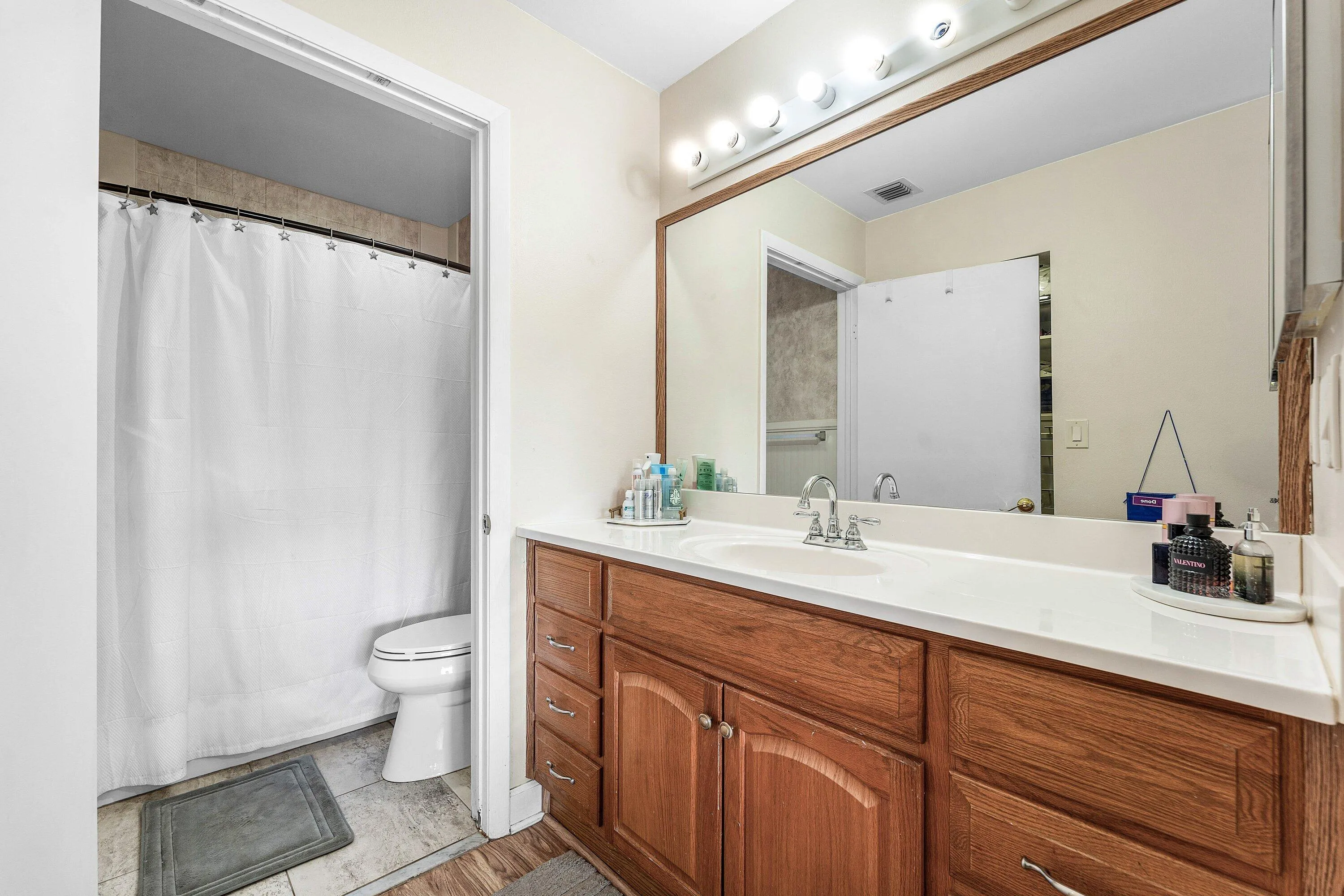 Bathroom vanity featuring a light wood-finish cabinet with a white countertop and integrated sink
