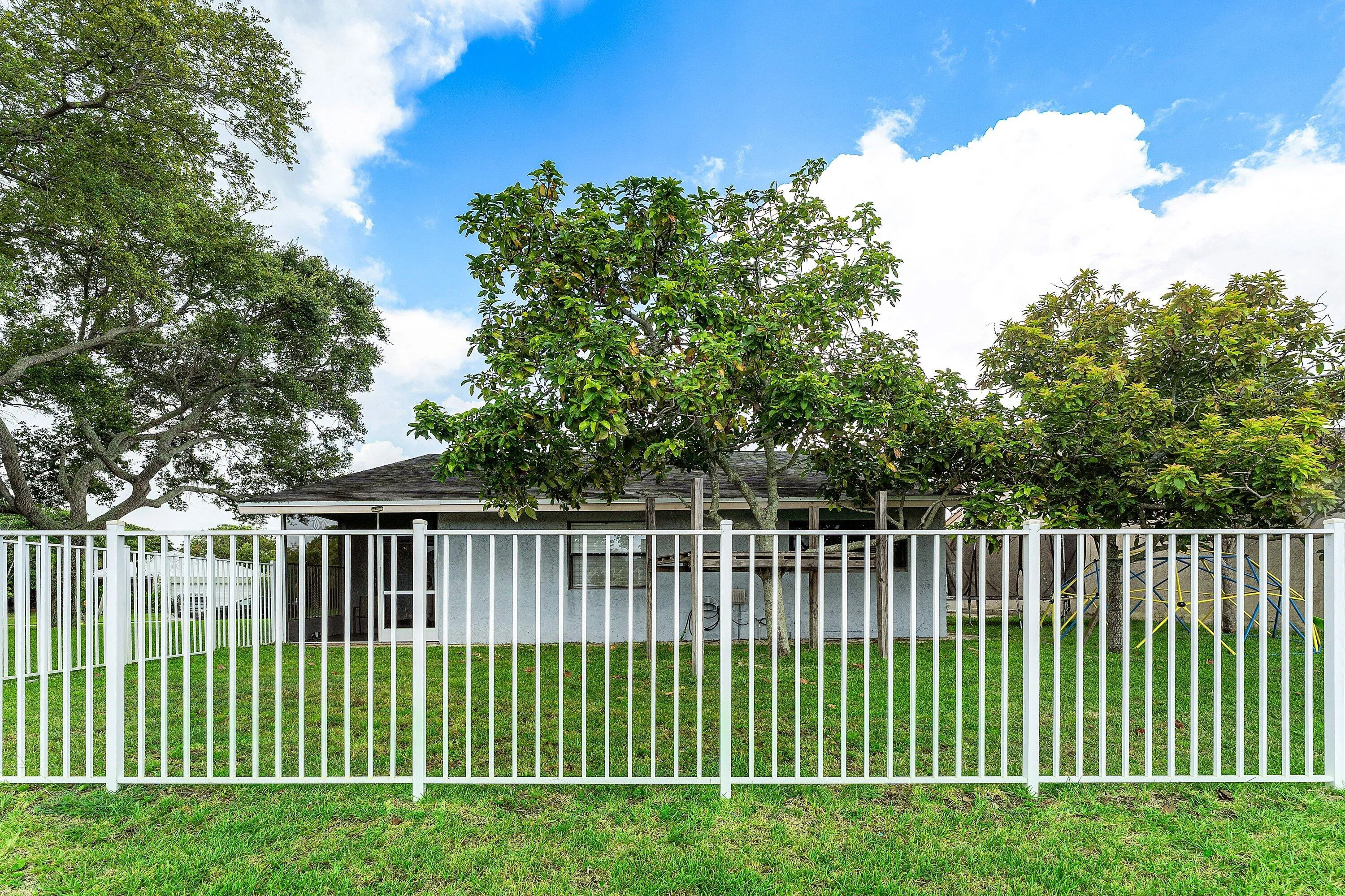 Rear exterior featuring a white metal fence enclosing a grassy yard