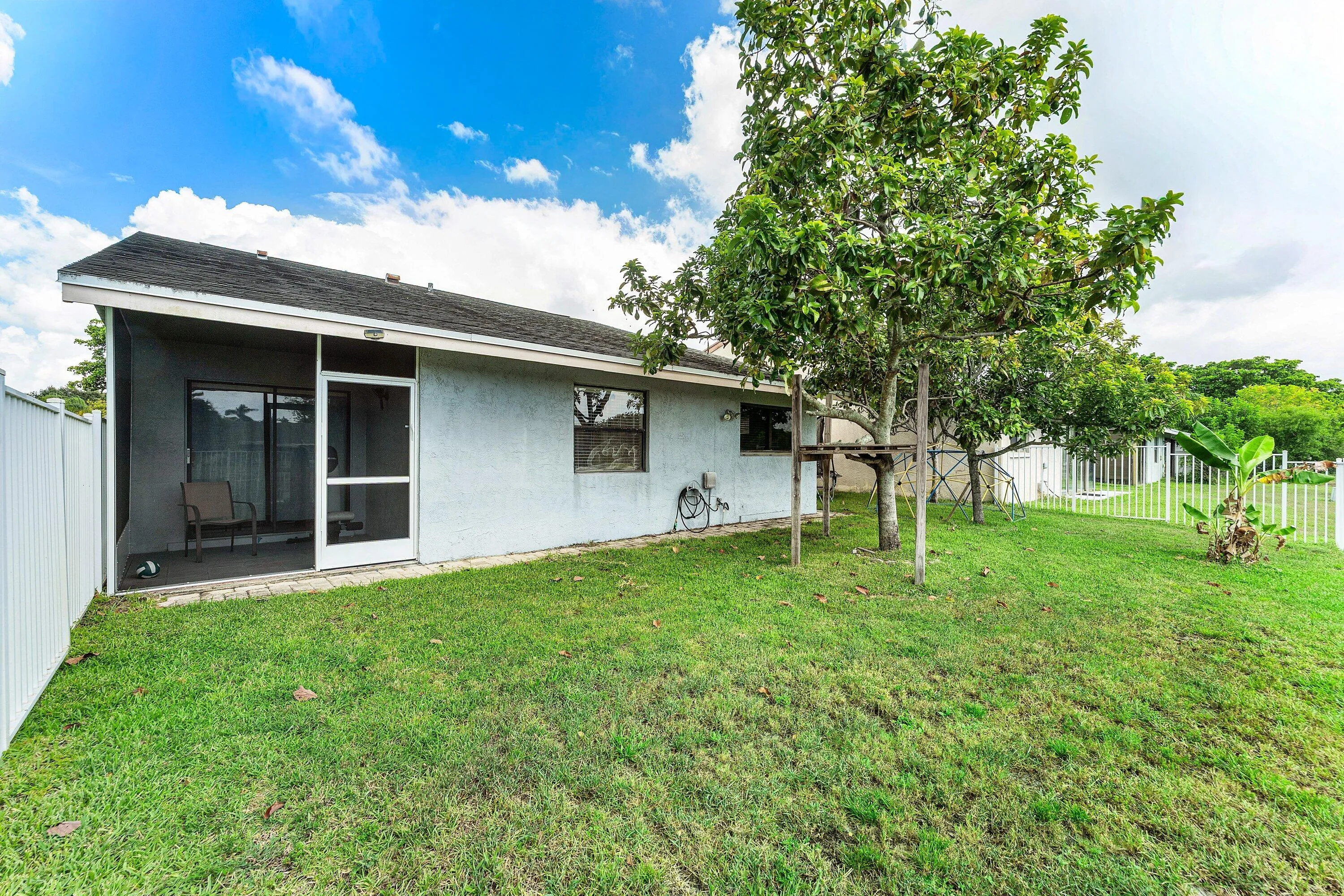 Rear exterior featuring a screened patio, sliding glass door, and a white privacy fence