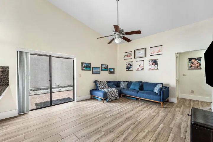 Vaulted ceiling living area featuring wood-finish flooring and a ceiling fan
