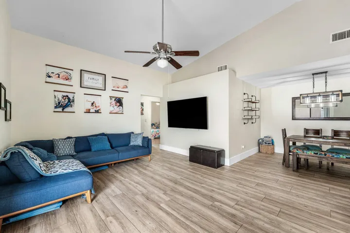 Expansive living area featuring vaulted ceilings, wood-finish flooring, and a contemporary ceiling fan