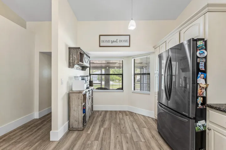 Bay window with horizontal blinds, overhead pendant lighting, wood-finish flooring, and built-in cabinetry