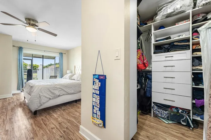 Bedroom featuring wood-finish flooring, a ceiling fan with integrated lighting, and a sliding glass door providing outdoor access