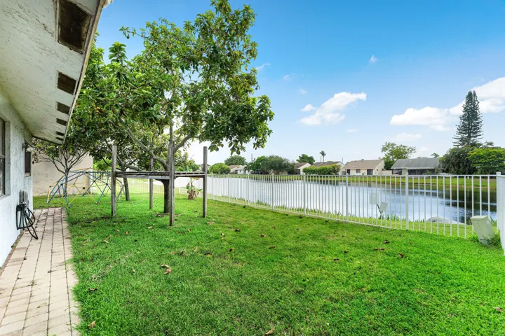 Expansive green lawn backing onto a pond, secured by a white perimeter fence