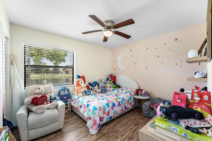 Bedroom featuring wood-finish flooring, a ceiling fan with light fixture, and a window with horizontal blinds